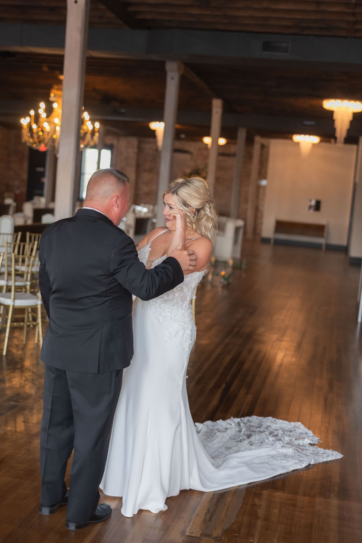 Couple dancing in a rustic indoor venue with exposed brick walls and hardwood floors.