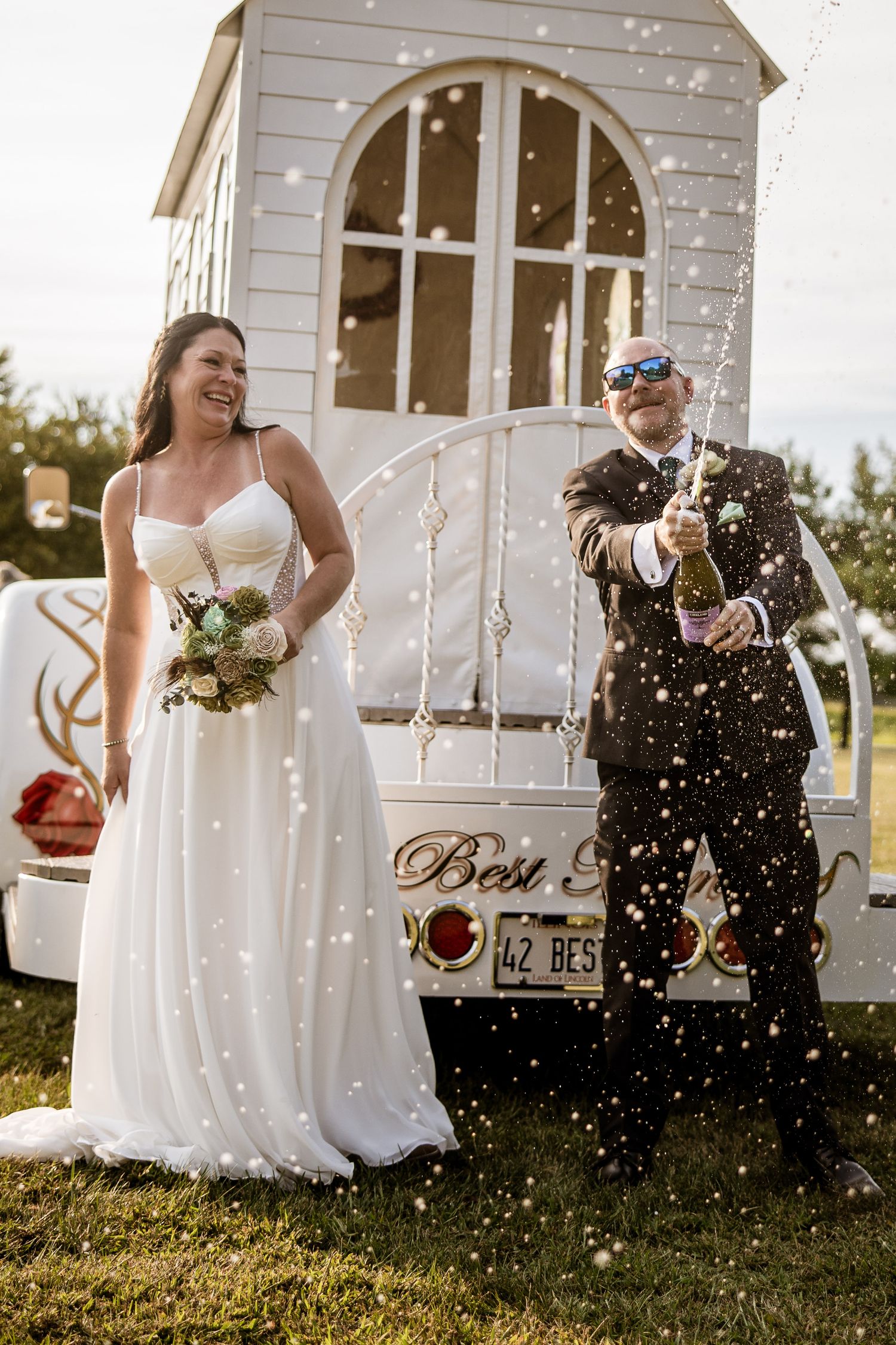 Wedding celebration with champagne spraying in front of a white gazebo.