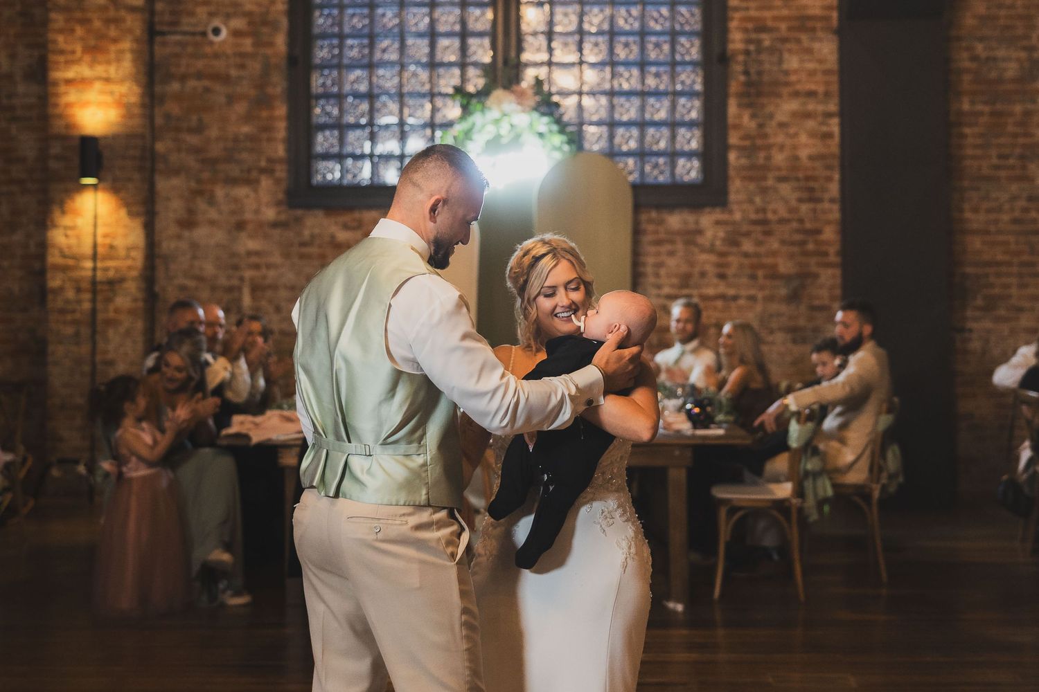 Wedding celebration in an industrial-chic venue with exposed brick walls and ambient lighting.