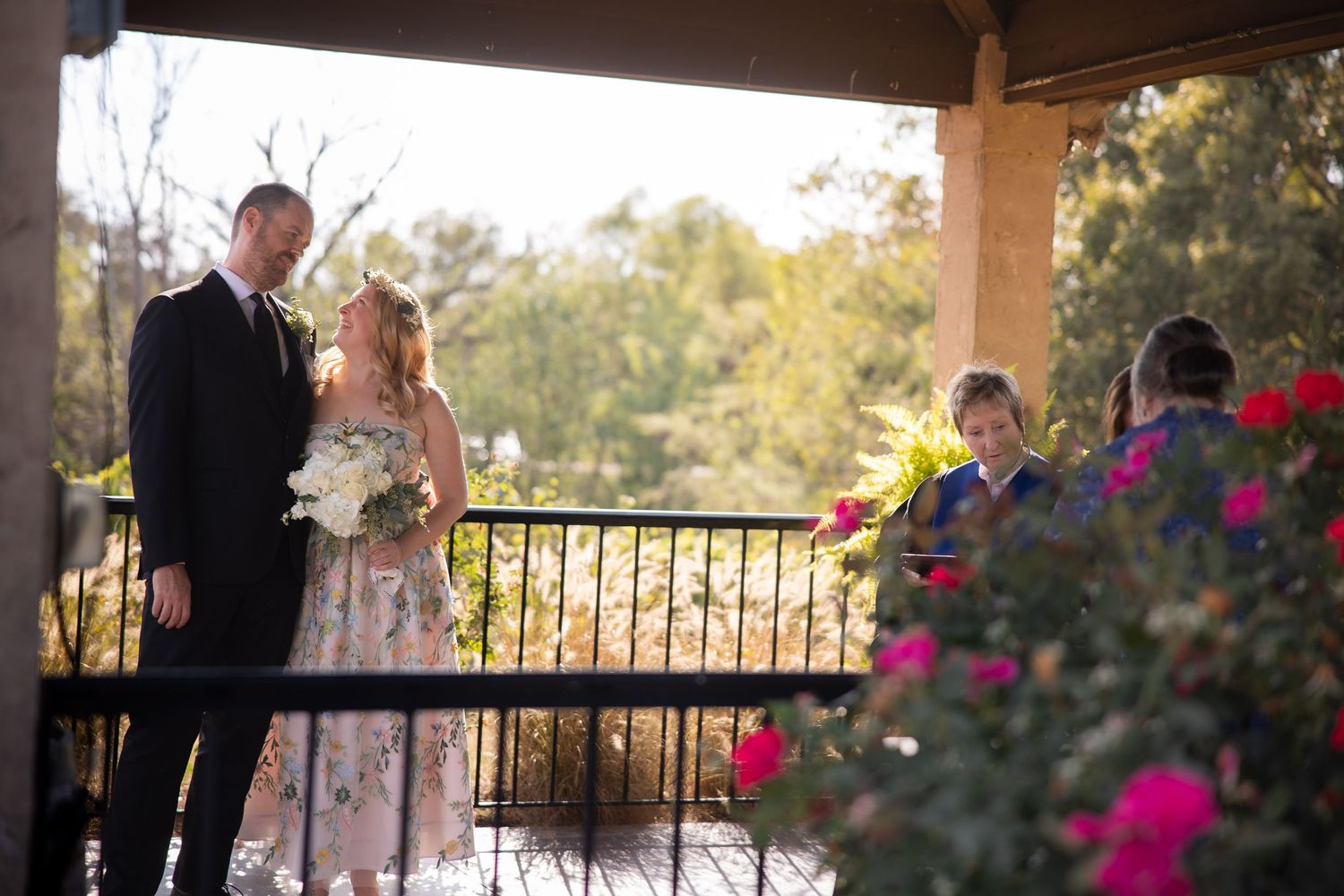 Outdoor wedding ceremony venue with covered patio and pink floral decorations.