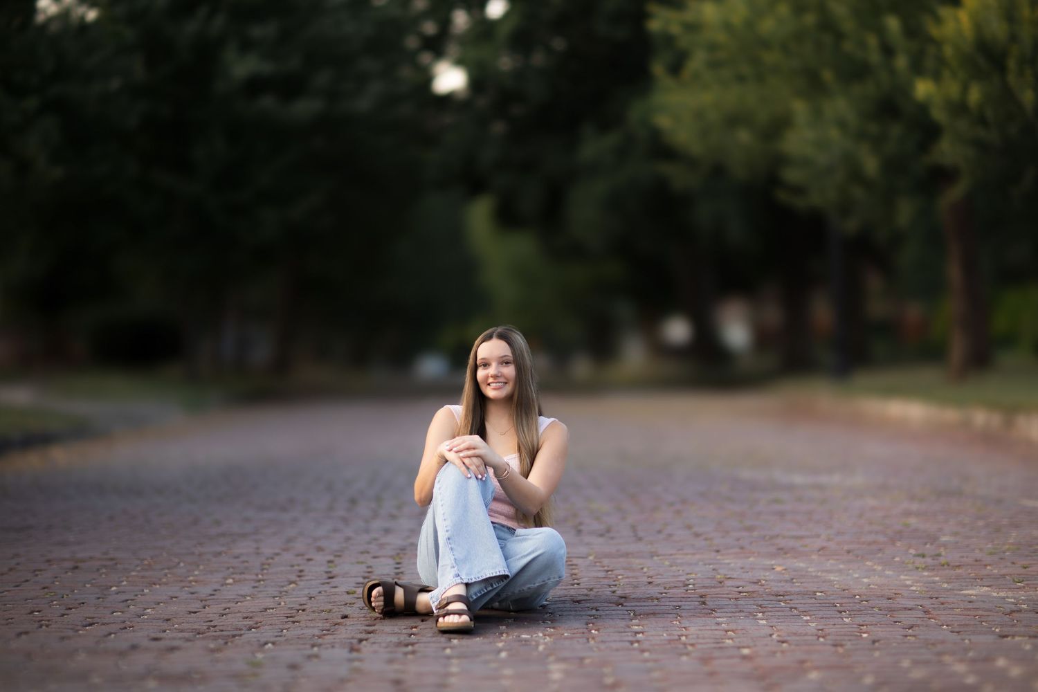Casual outdoor portrait session on a paved path surrounded by trees.