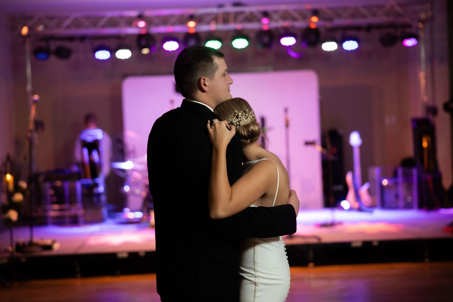 Wedding reception dance floor illuminated with purple and pink stage lighting.