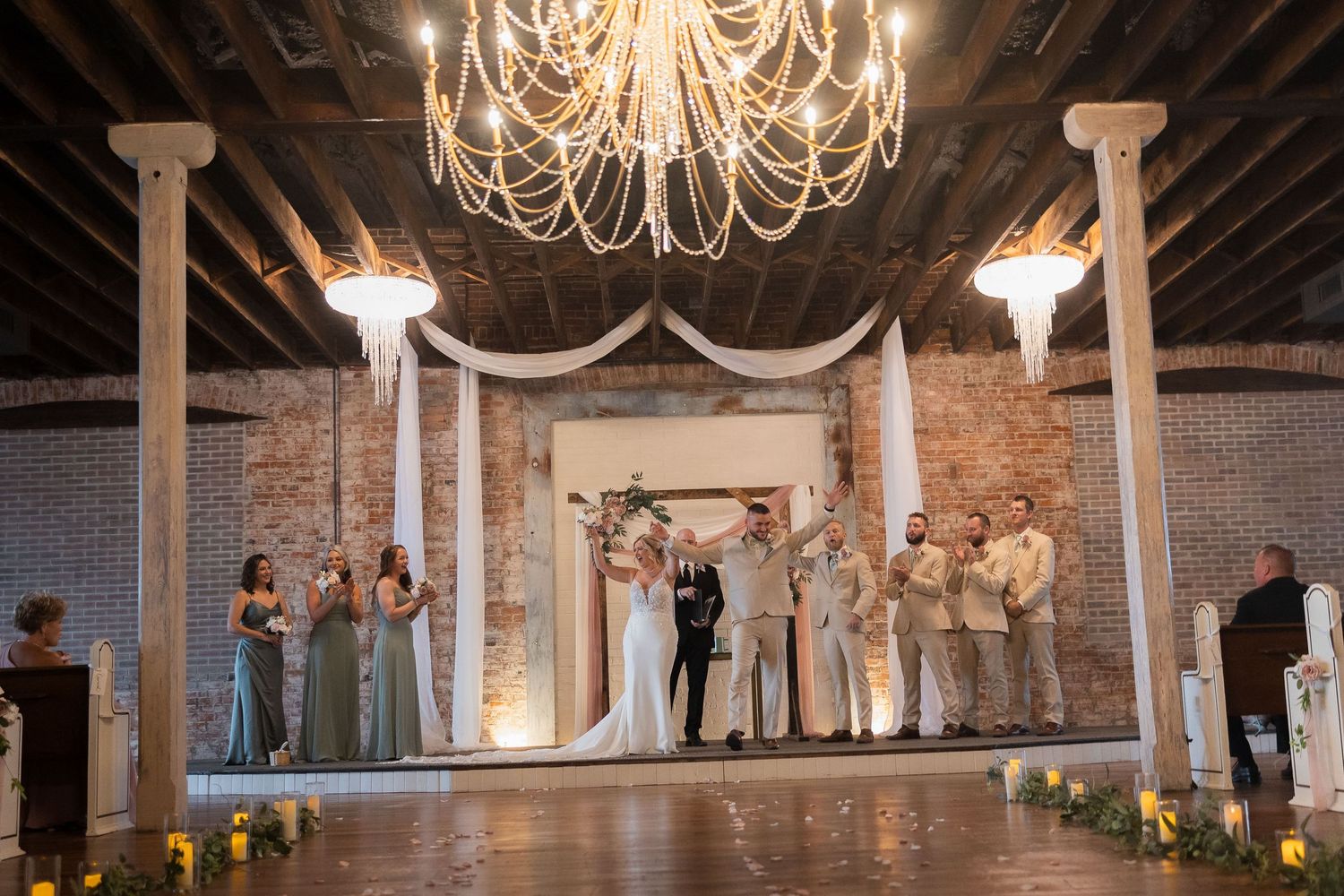 Elegant wedding venue interior with exposed brick walls and crystal chandeliers creating a romantic atmosphere.