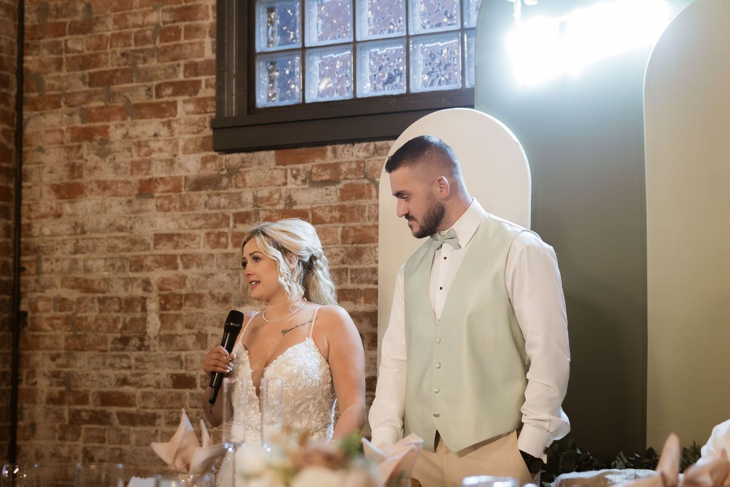Elegant indoor wedding ceremony space with exposed brick walls and natural window light.
