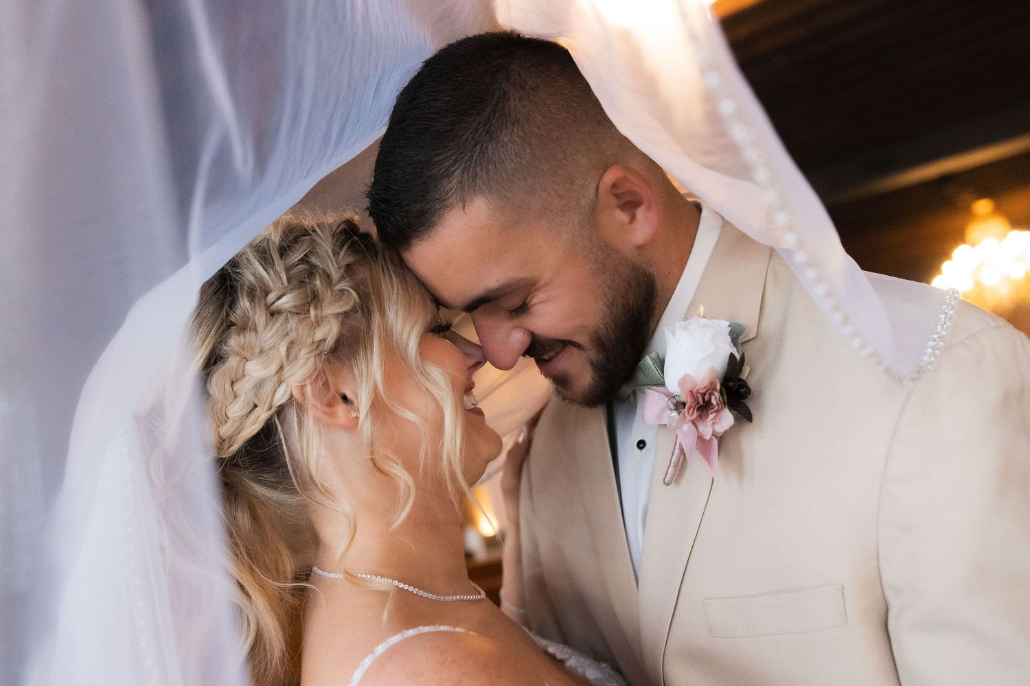 Romantic wedding couple shares intimate moments in elegant venue with soft lighting and classic decor.