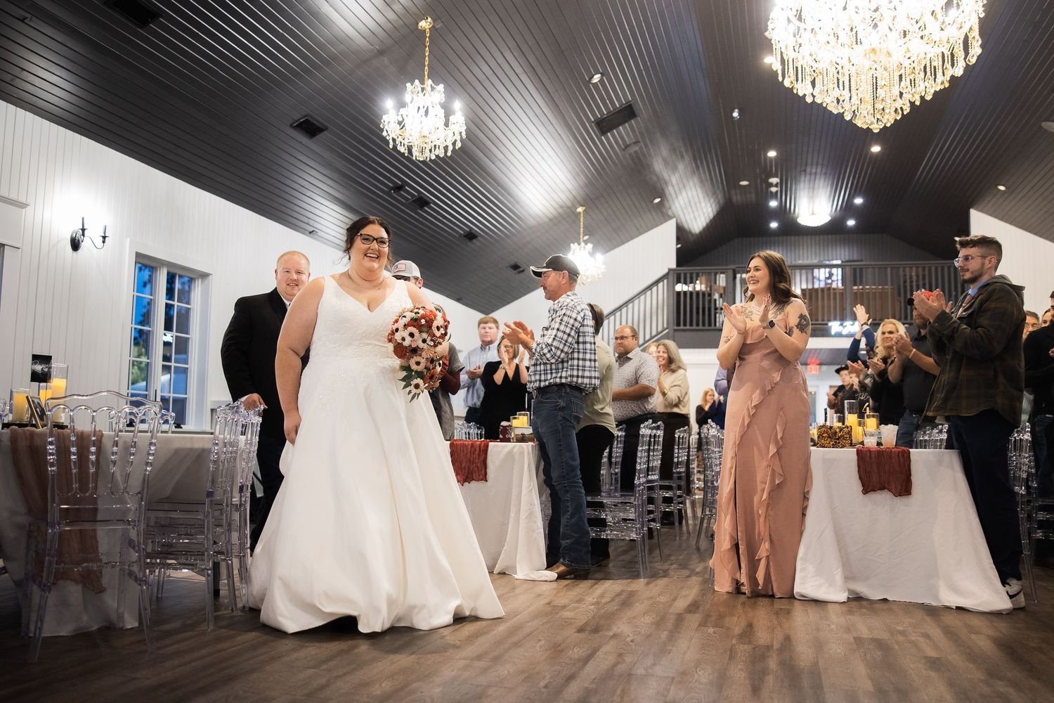 Wedding reception venue decorated with elegant crystal chandeliers and white tables set for dining.