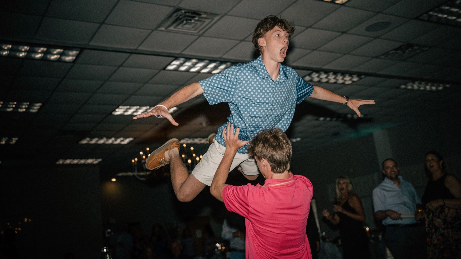 Guest is lifted in the air by another guest on a lively wedding dance floor.