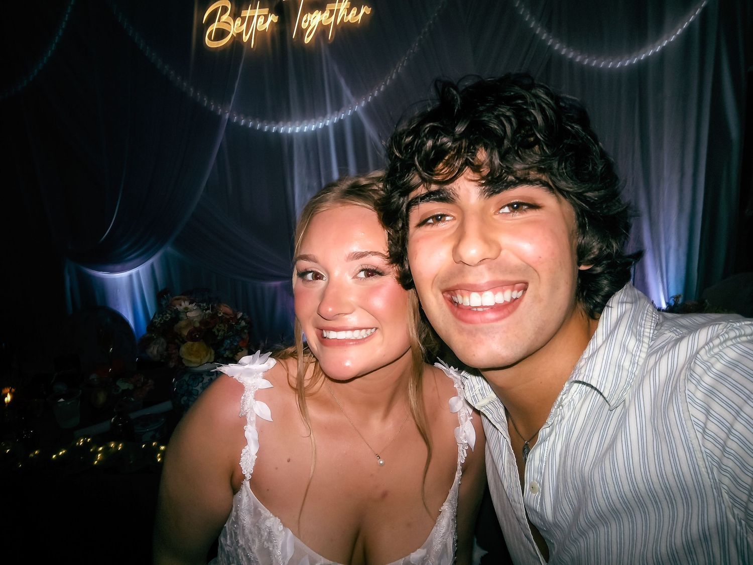 Smiling couple posing together at a wedding reception under Better Together sign.