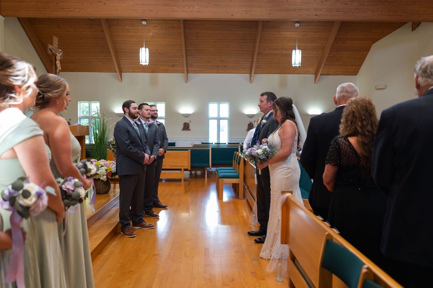 Bride and groom stand at the altar during a church wedding ceremony with bridesmaids and groomsmen lined up.