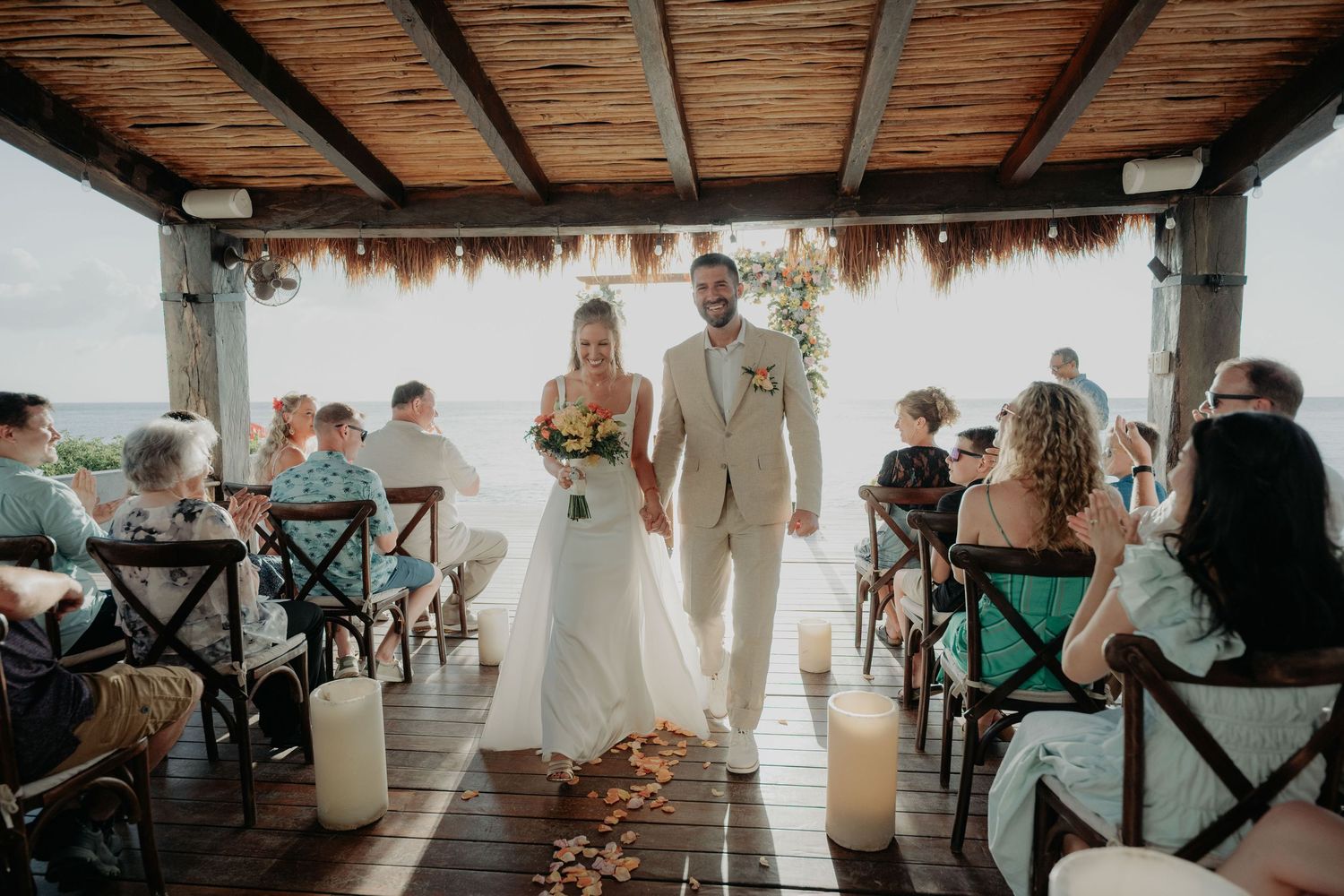 Wedding reception venue with wooden beams and rustic decor filled with celebrating guests.