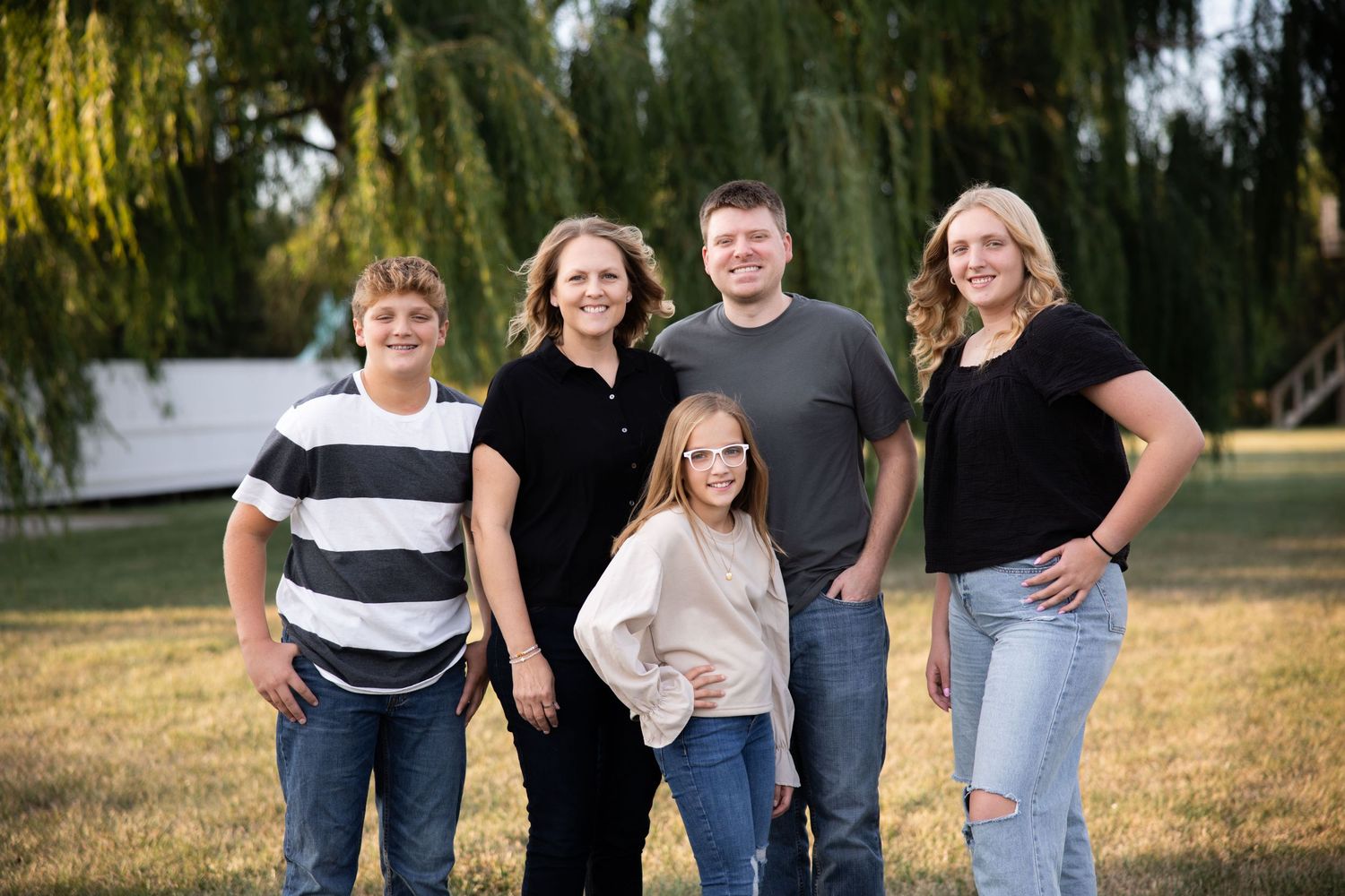 Family group portrait taken under weeping willow trees at sunset.