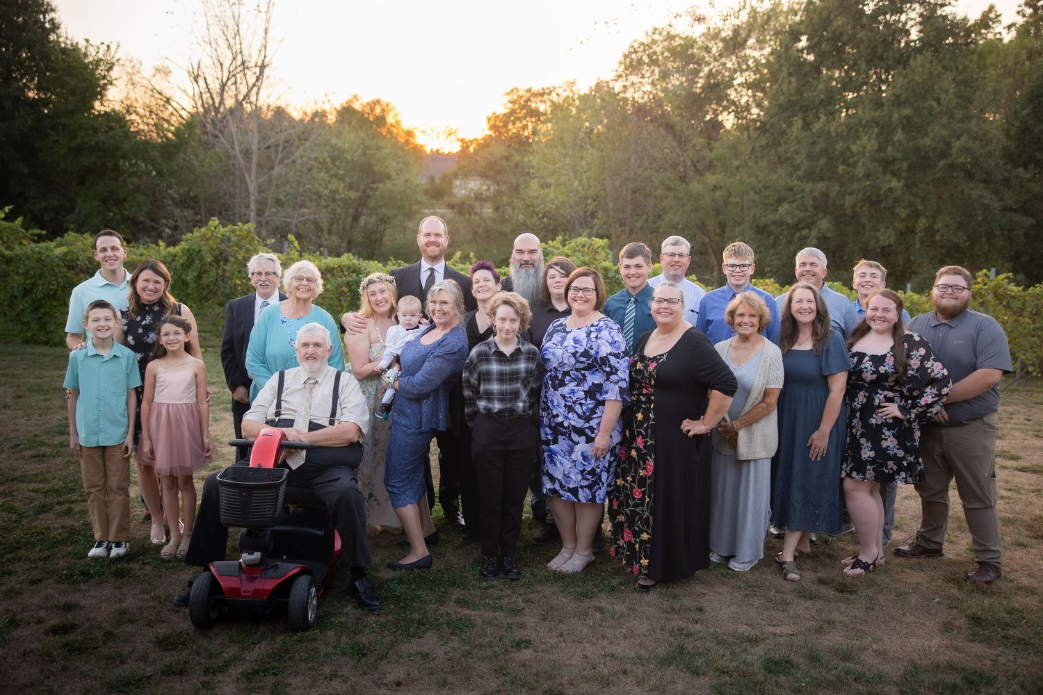 Large group photo of wedding guests gathered outdoors at sunset.