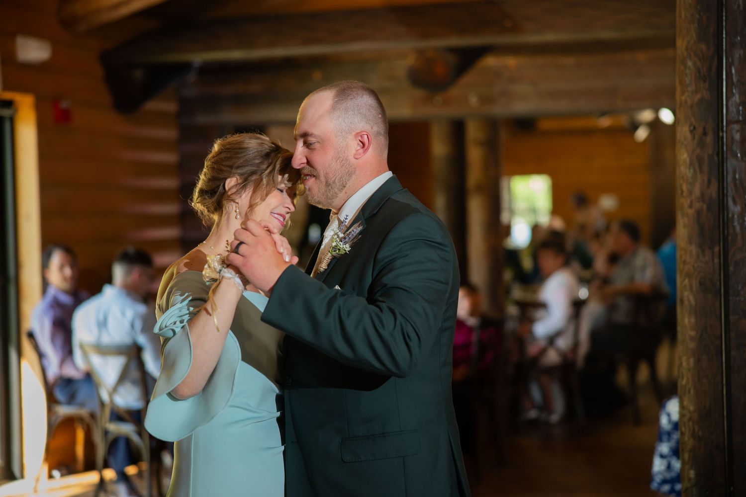 Bride and groom sharing intimate first dance in rustic log cabin wedding reception venue.