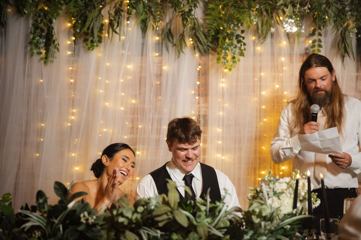 Wedding reception setup with hanging greenery and string lights creating a romantic atmosphere.