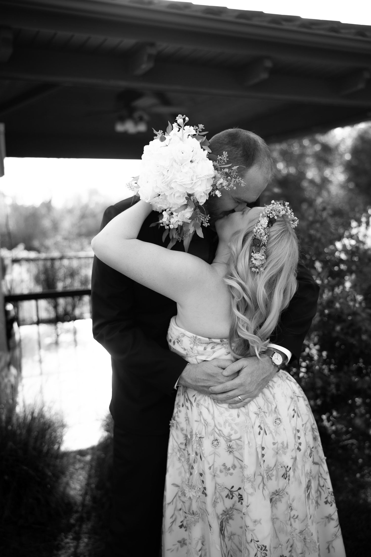 Black and white photo of a couple dancing in formal attire at an outdoor wedding.