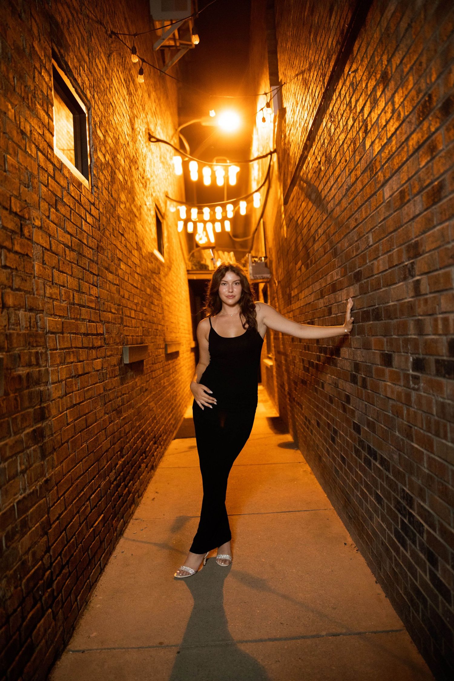 Artistic sequence of someone walking through a dimly lit brick corridor with warm overhead lighting.