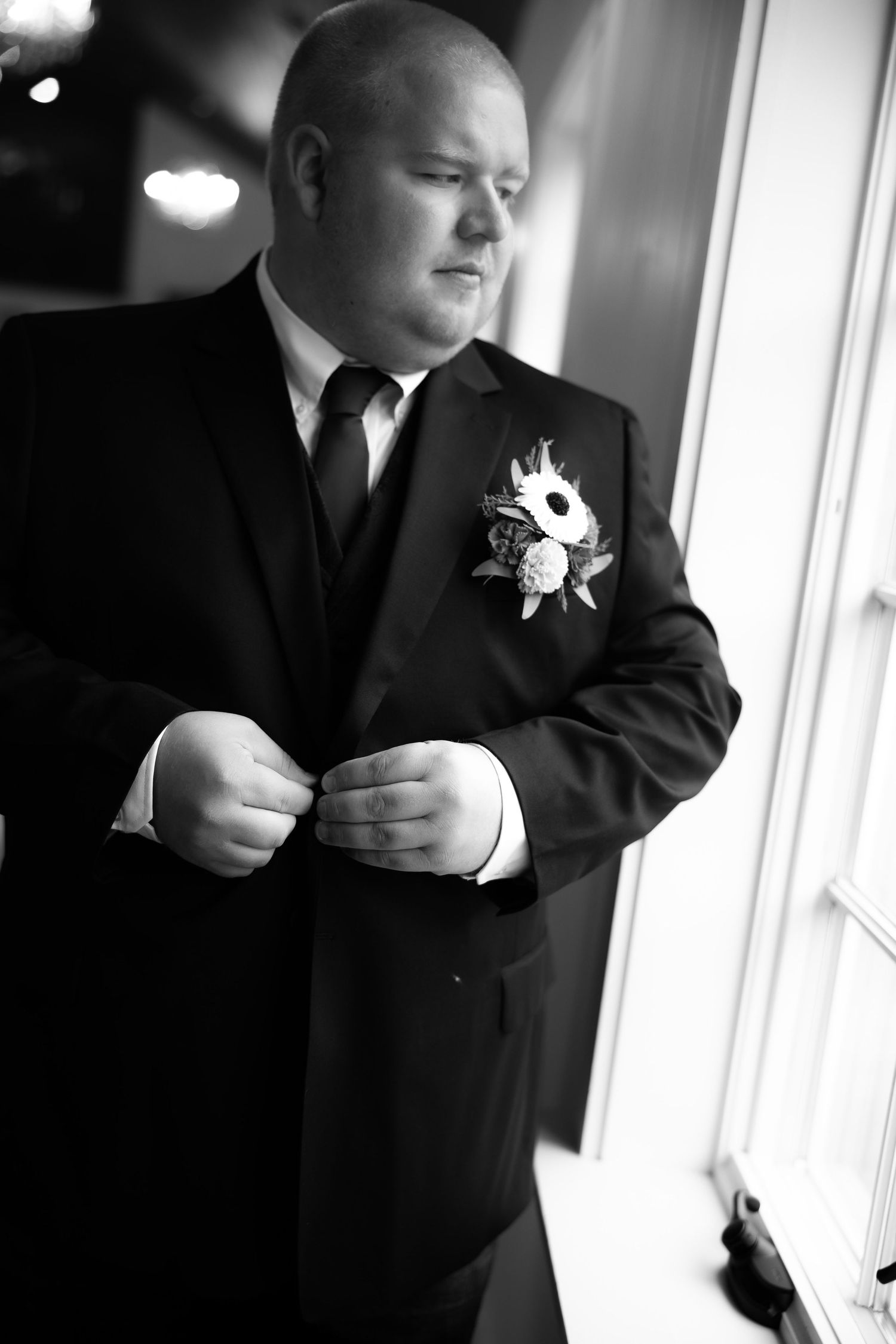 A series of black and white photos showing someone adjusting a formal suit jacket and boutonniere.