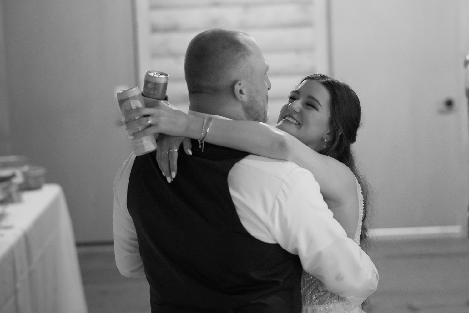 Bride and groom sharing an intimate first dance embrace at wedding reception in black and white.