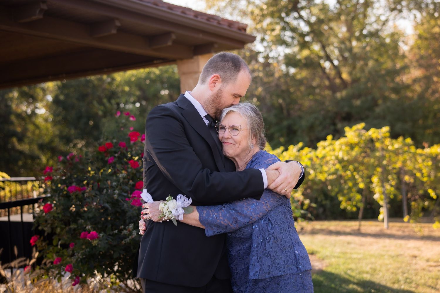 Two people embrace during an emotional moment at an outdoor wedding venue.