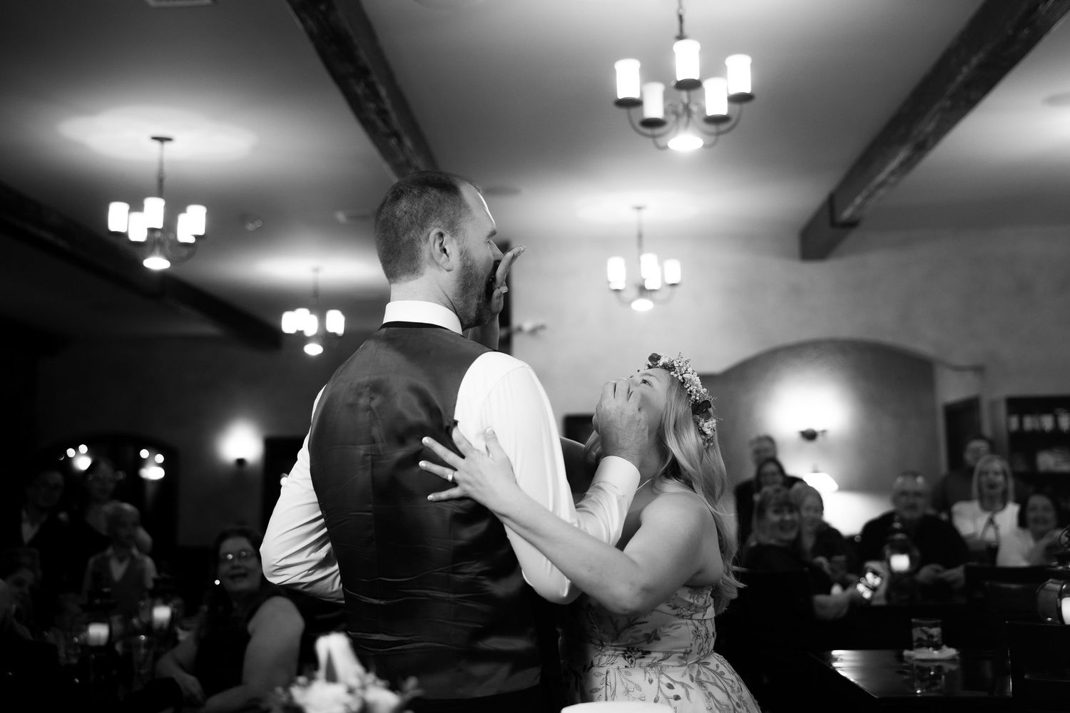 Wedding guests dancing together on a dimly lit dance floor at an evening reception celebration.