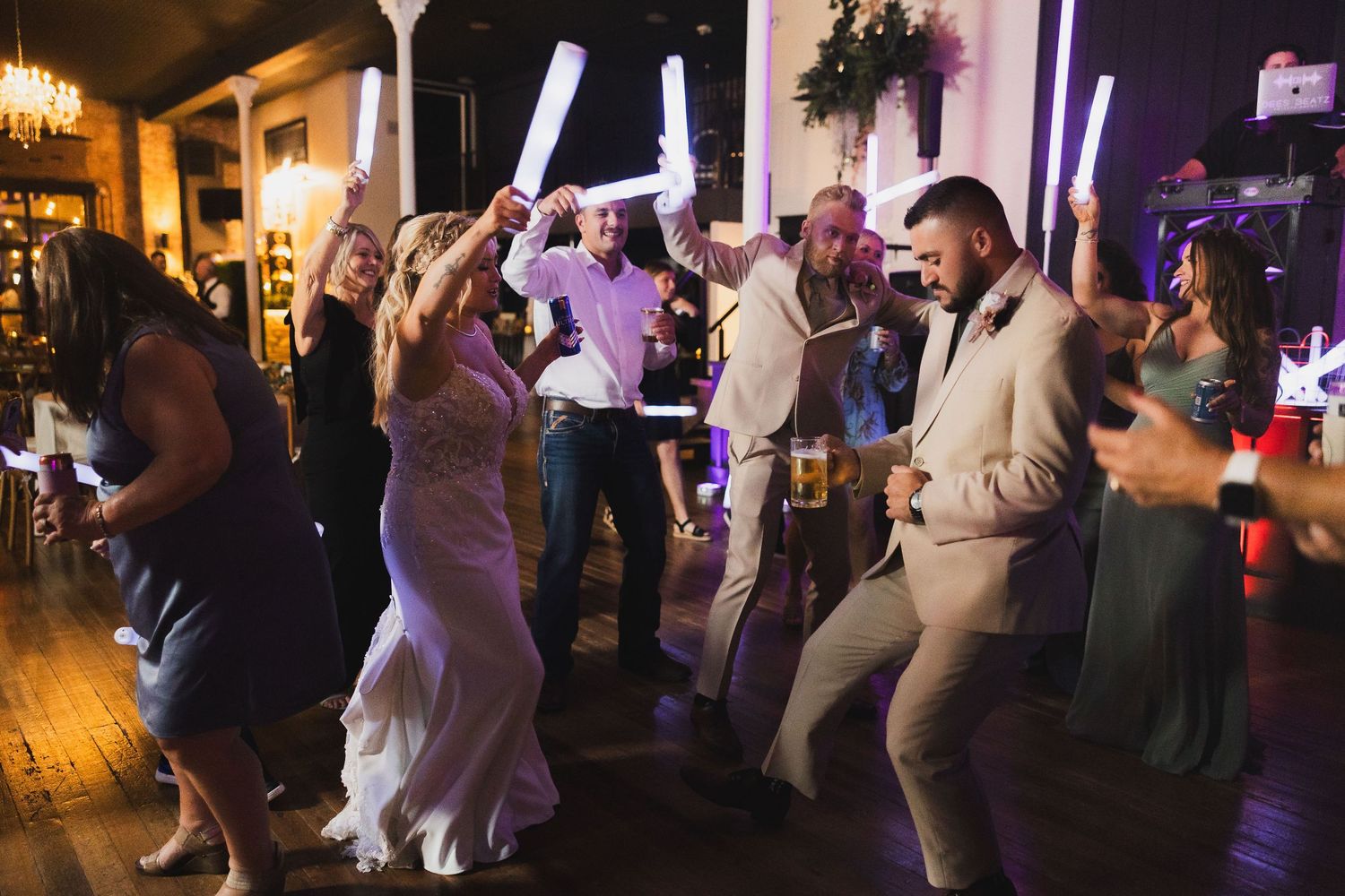 Wedding reception dance party with colorful lighting and guests celebrating on the dance floor.