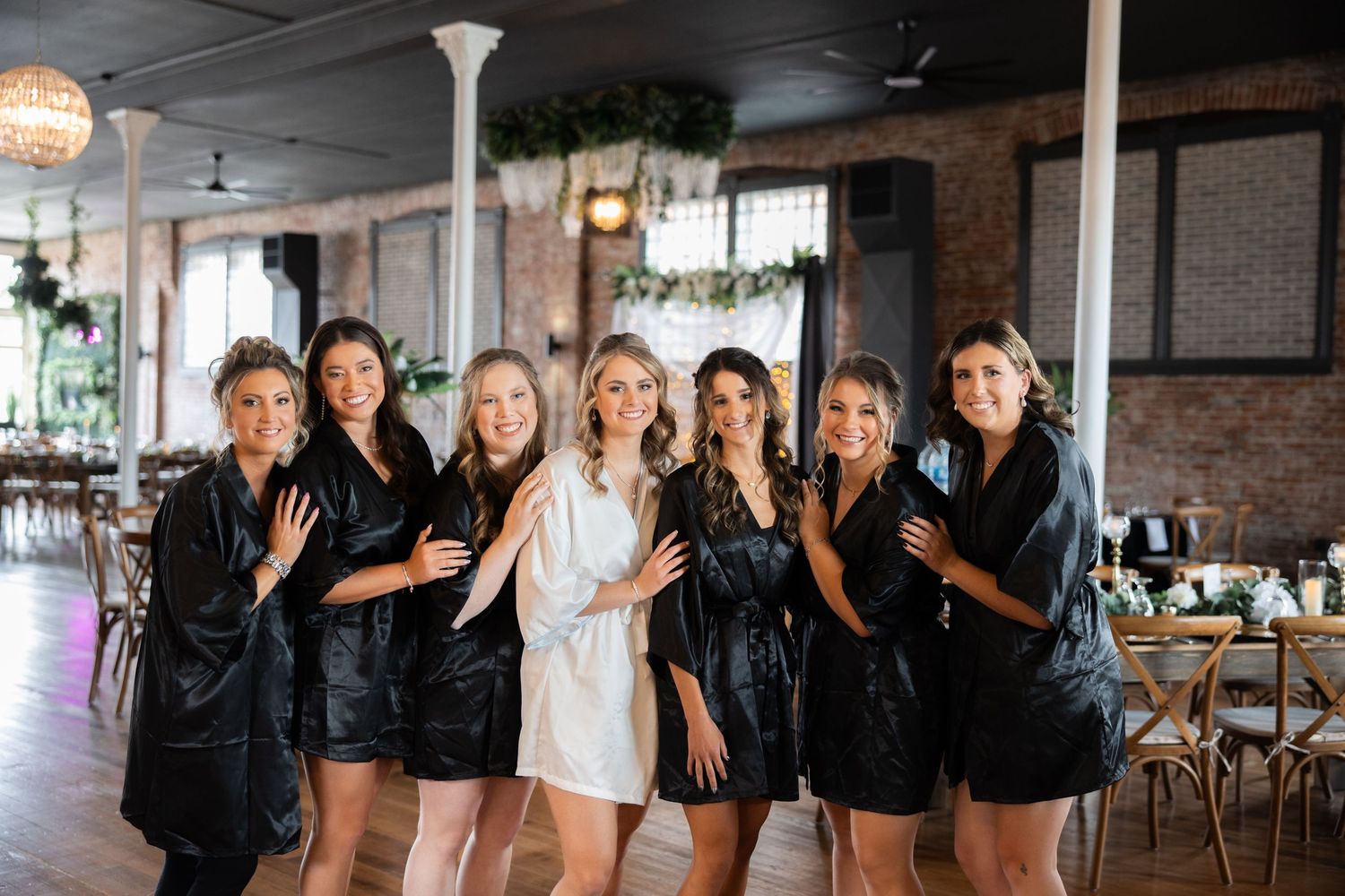 Wedding party photo showing bridesmaids in black dresses with bride in white.