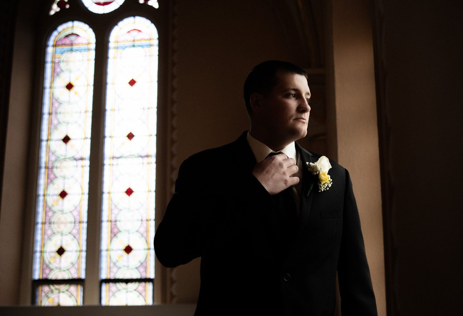 Dramatic silhouette wedding photos with stained glass windows in church setting.