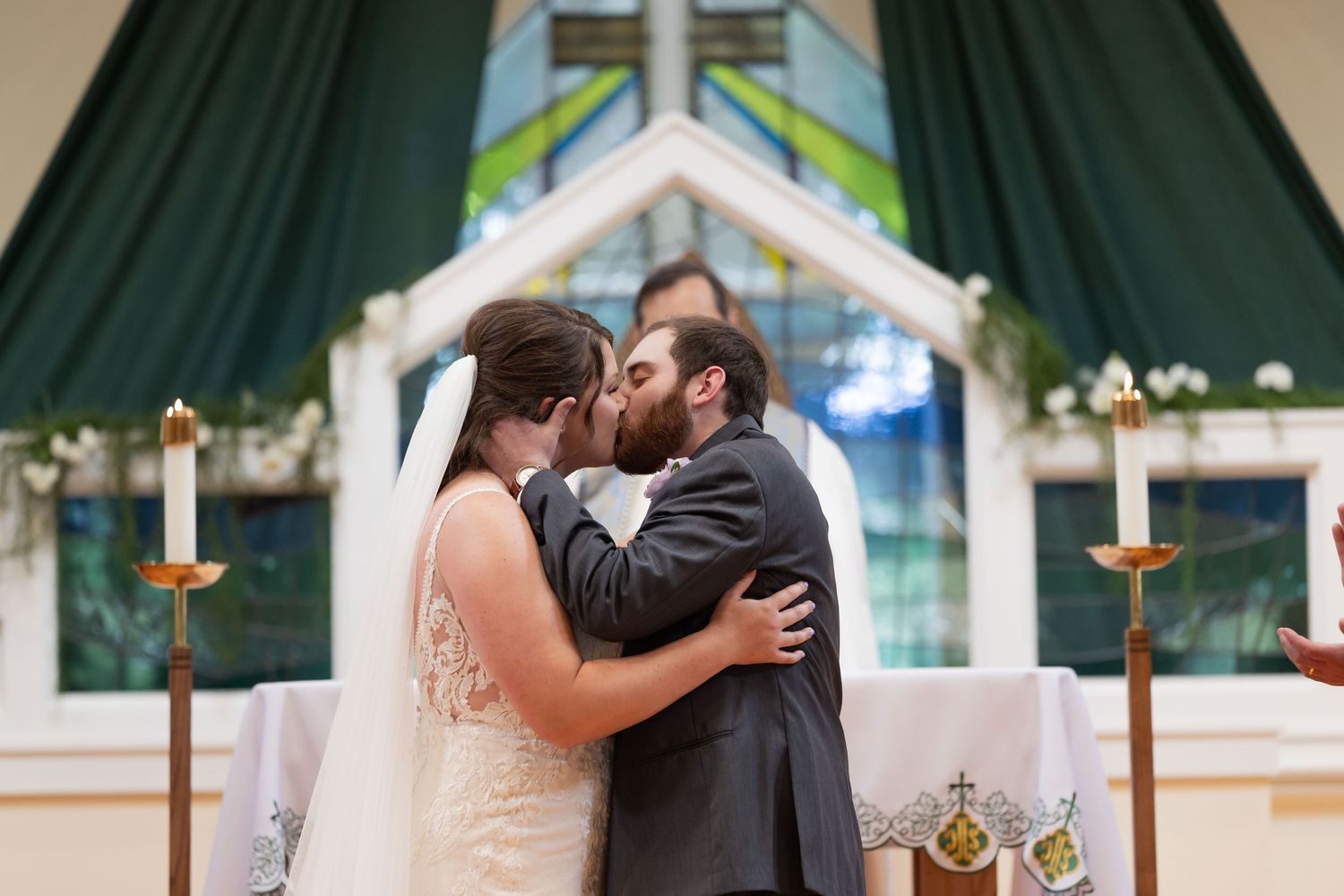 Bride and groom share their first kiss at the altar during a church wedding ceremony.