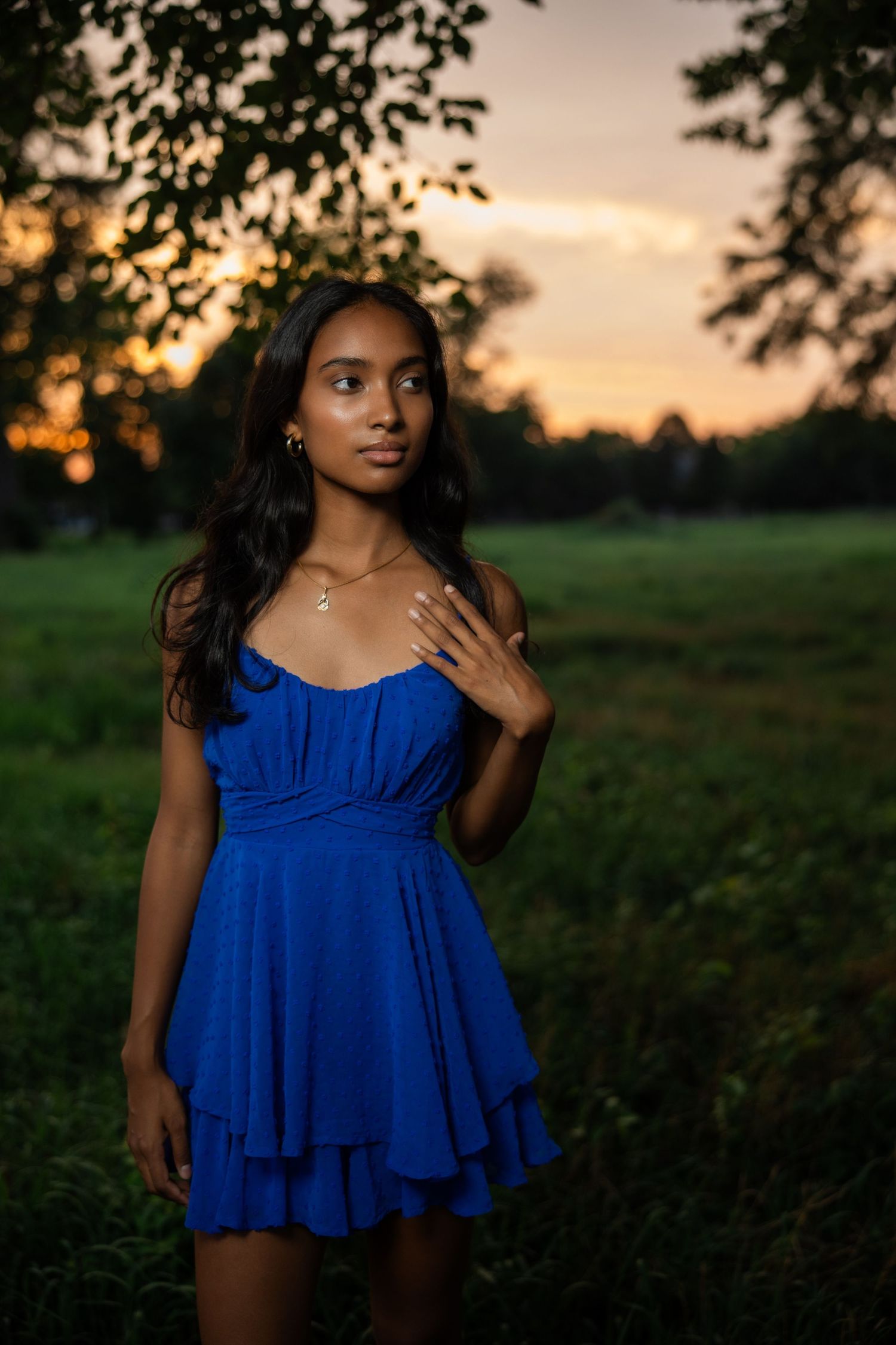 A blue ruffle dress photographed during golden hour sunset in a grassy field.