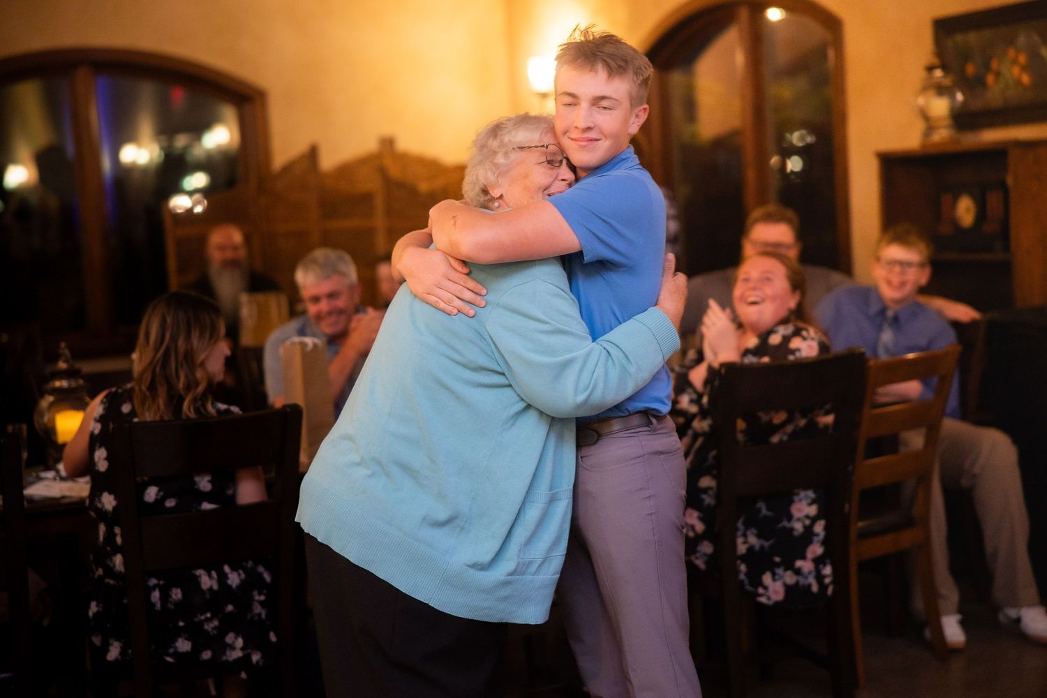 People embracing while dancing at an evening social event with warm lighting.