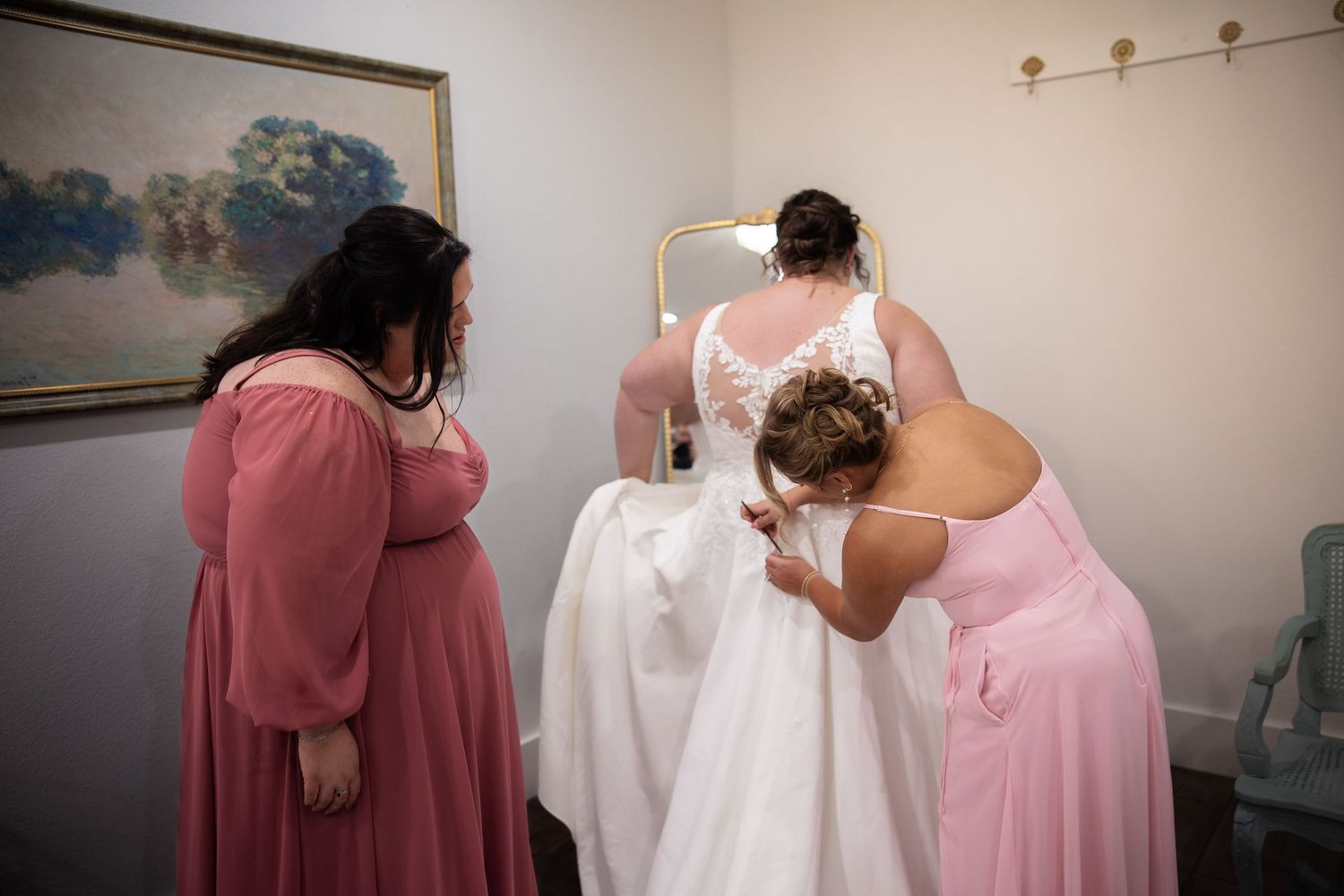 A group in pink and white dresses stand together while getting ready for a formal event.