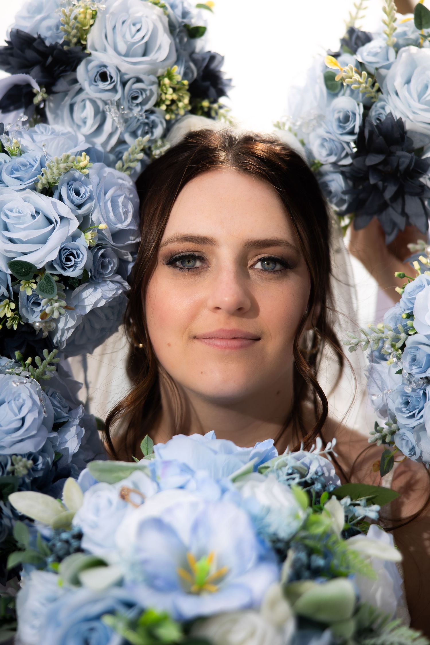 Beautiful bride surrounded by elegant blue rose bouquets at her wedding ceremony.