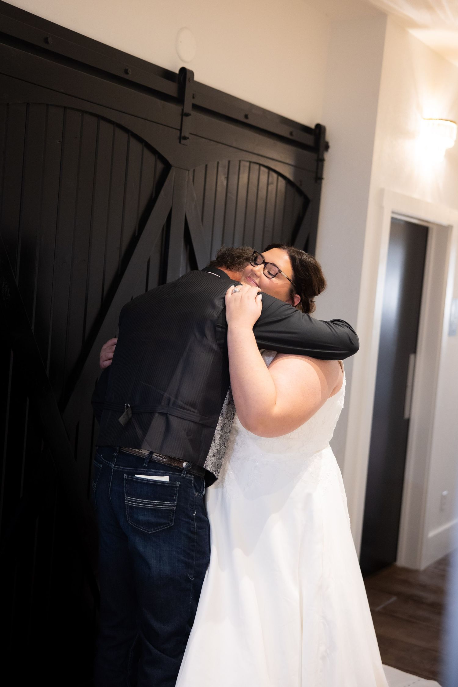 A tender embrace between a couple on their wedding day in front of black barn doors.