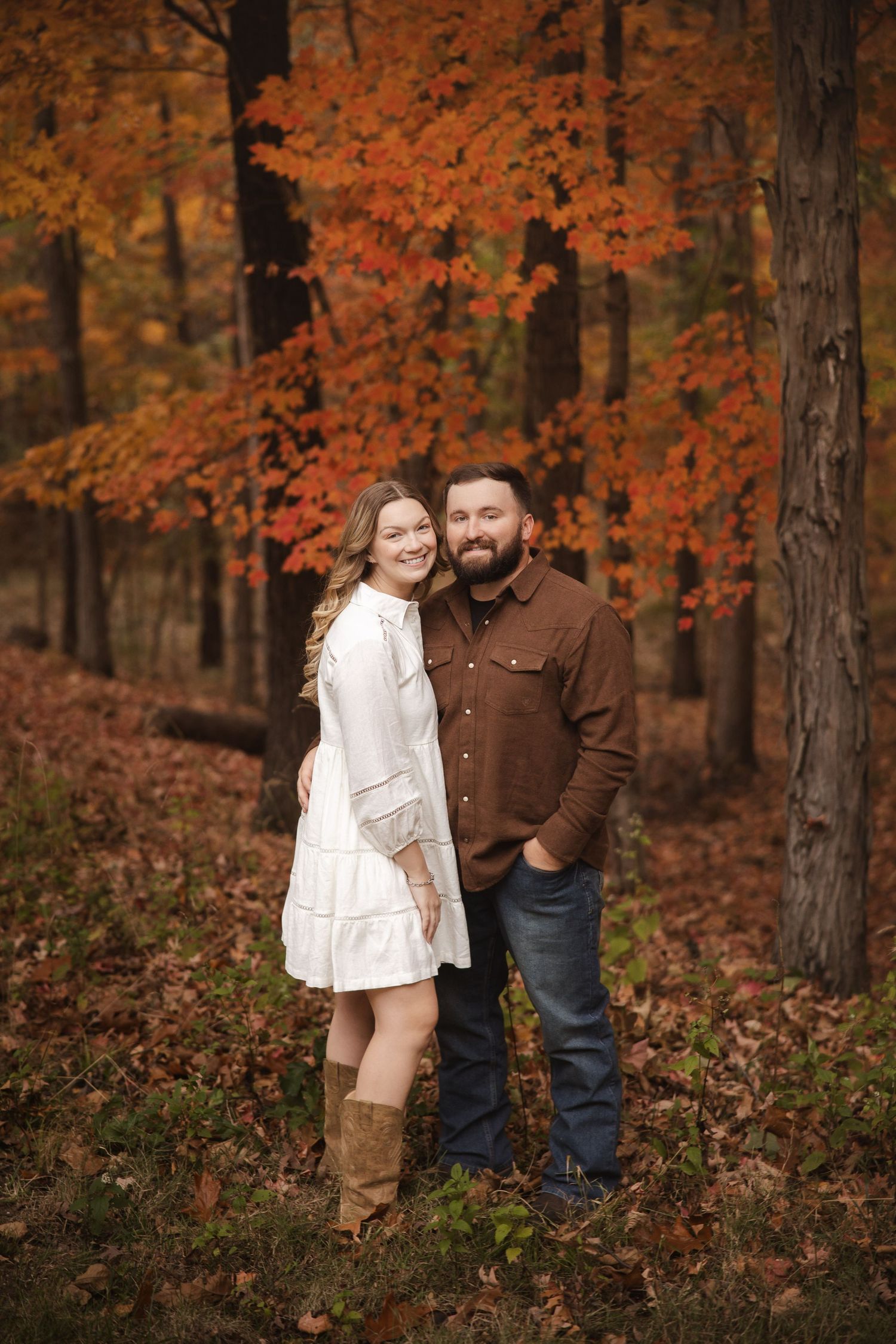 A romantic autumn portrait with vibrant orange foliage creates a stunning backdrop for a couple's photoshoot.