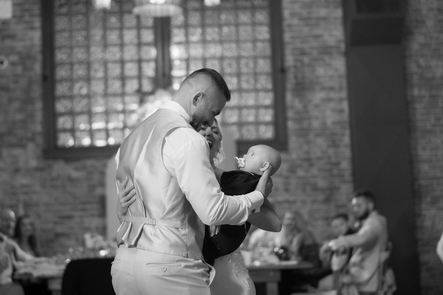 Wedding reception dance floor moments captured in black and white at an industrial-style venue.