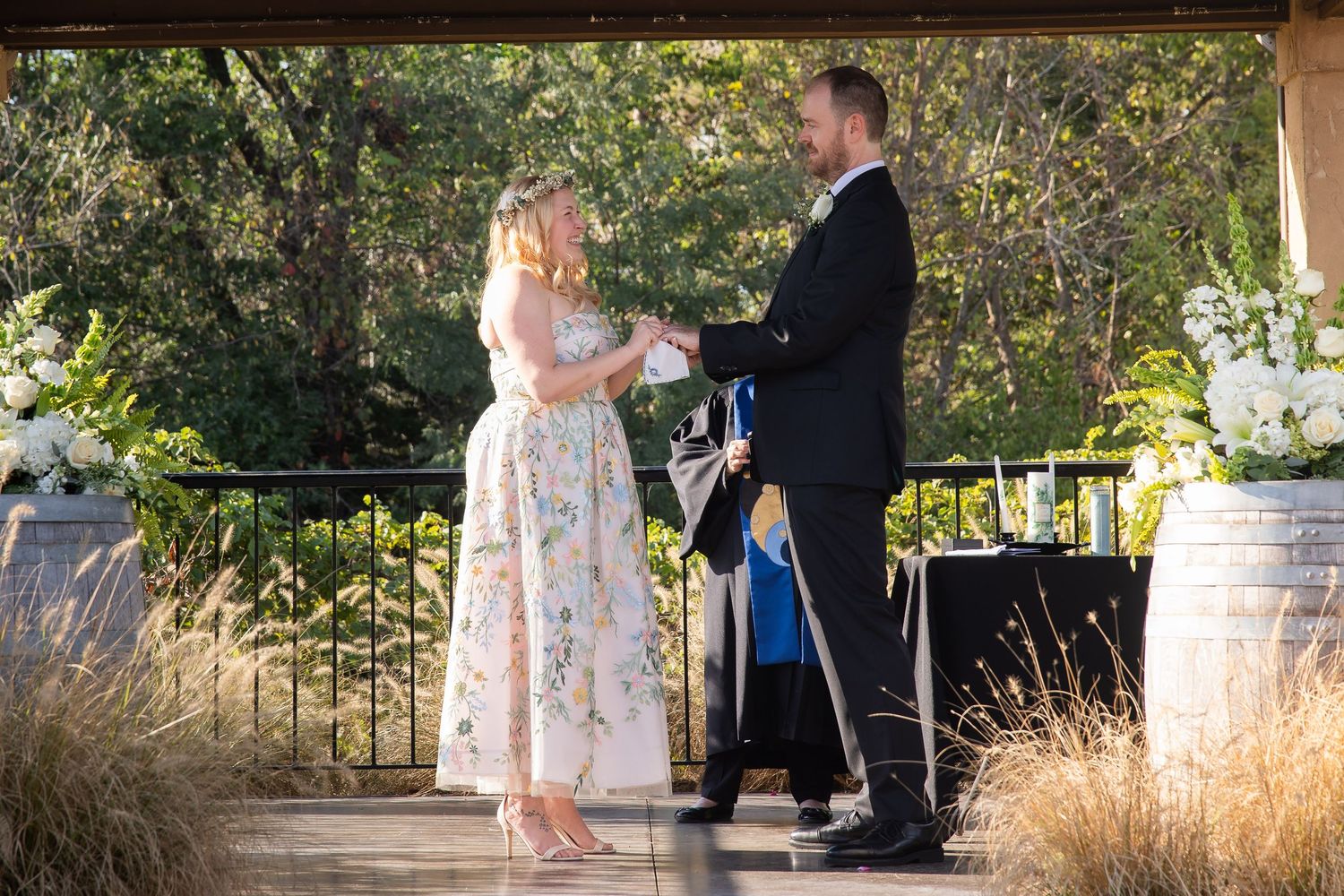 A couple shares an intimate outdoor moment in a garden setting during a wedding ceremony.