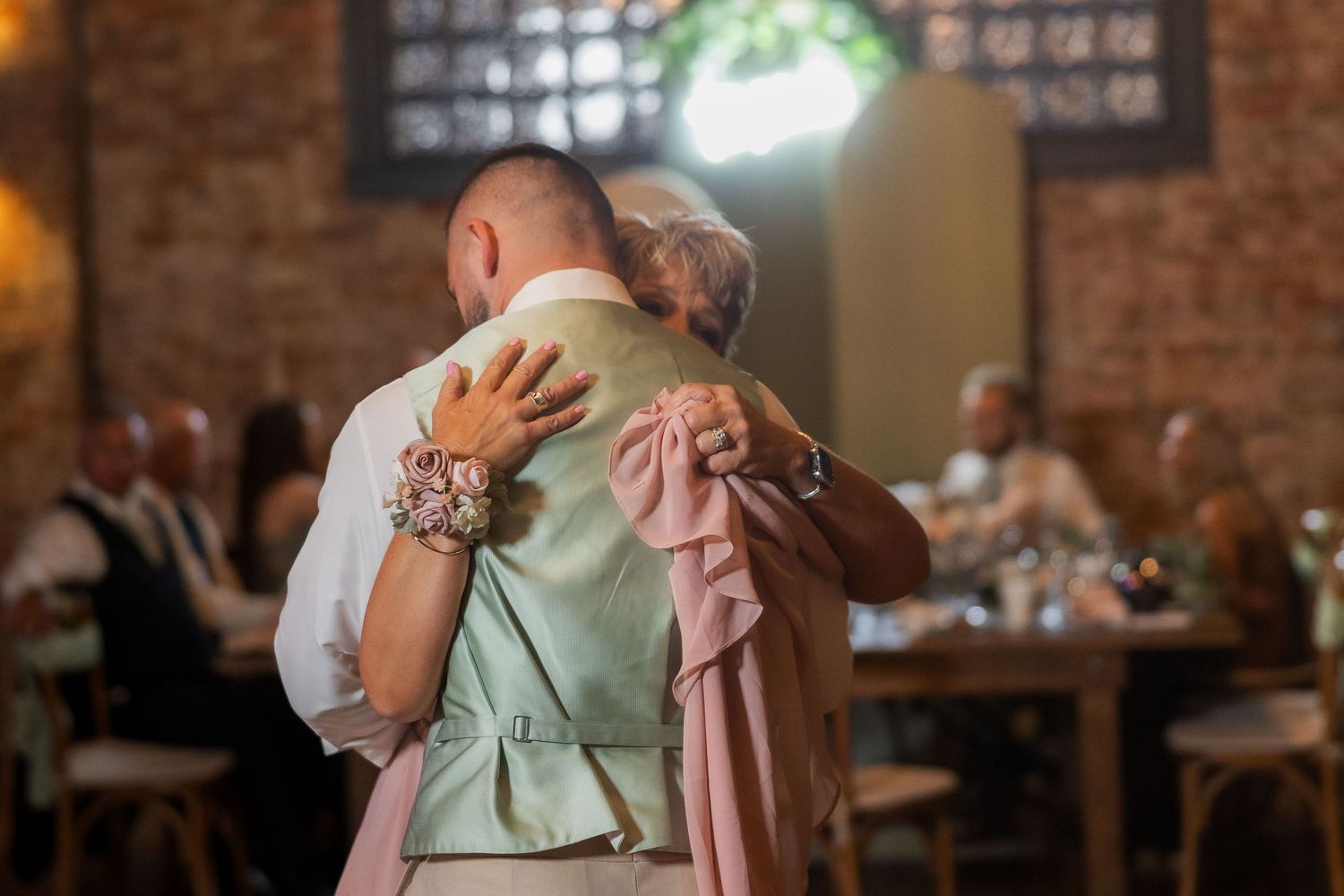 Wedding reception dance captured in warm ambient lighting with exposed brick walls.
