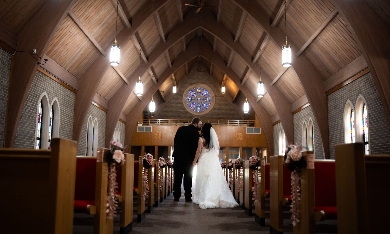 Long exposure shot of a dimly lit church hallway with vaulted ceilings and hanging lights.