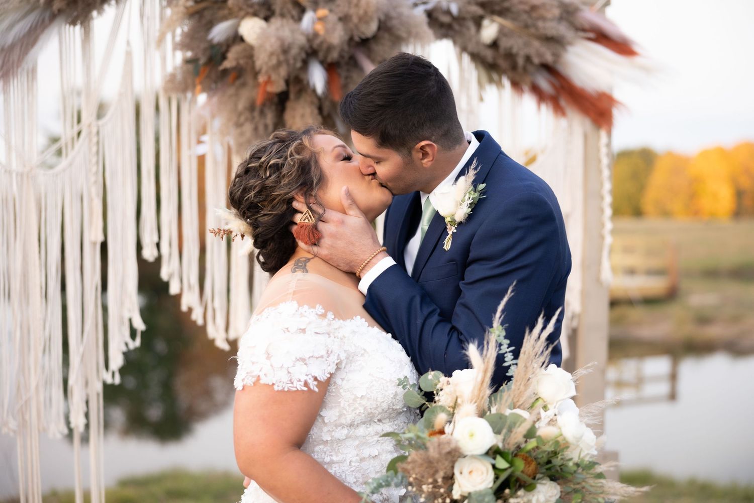 Elegant wedding ceremony decor with white macrame hangings and dried floral arrangements.