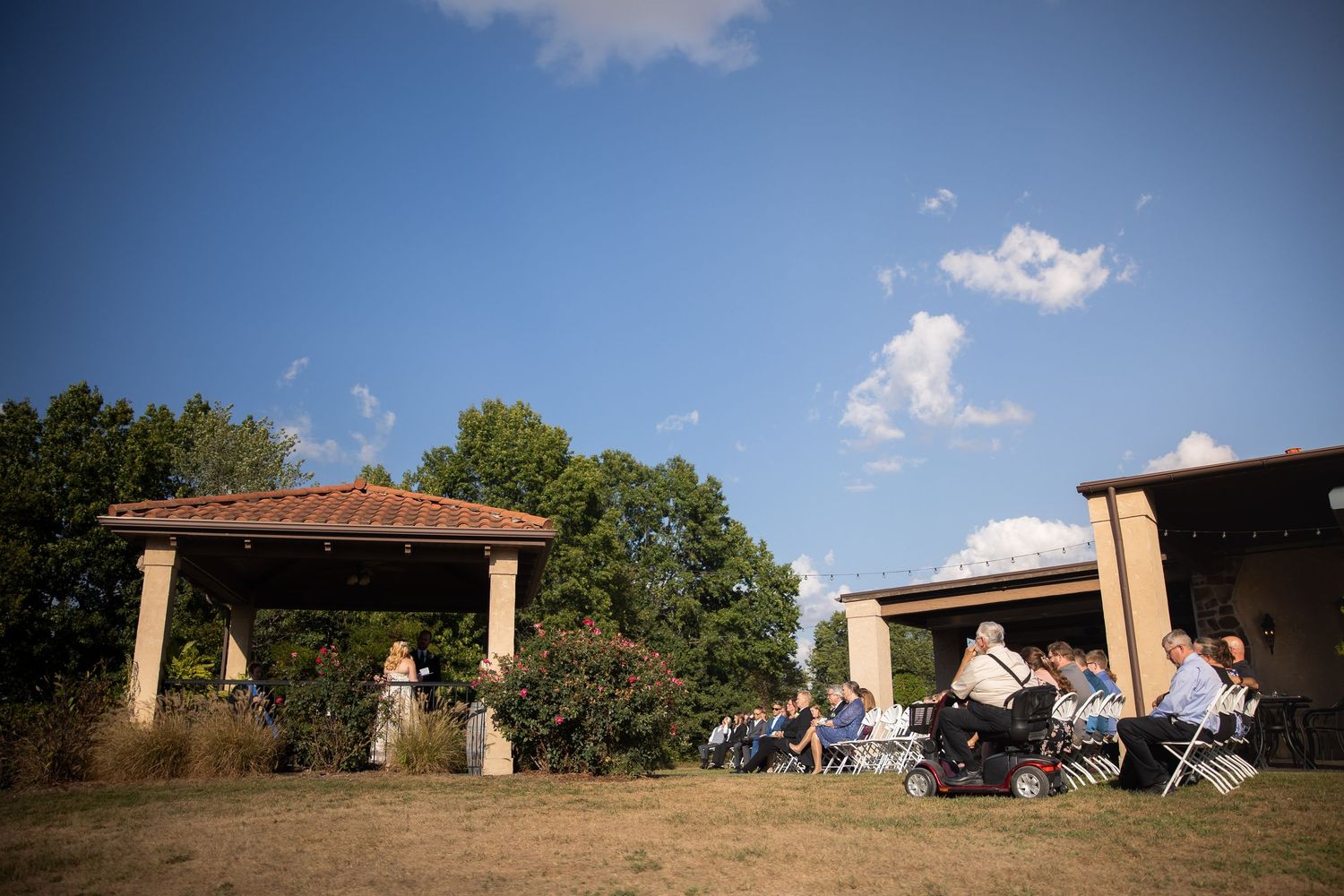 Panoramic view of a rustic wedding venue with stone columns and blue sky.