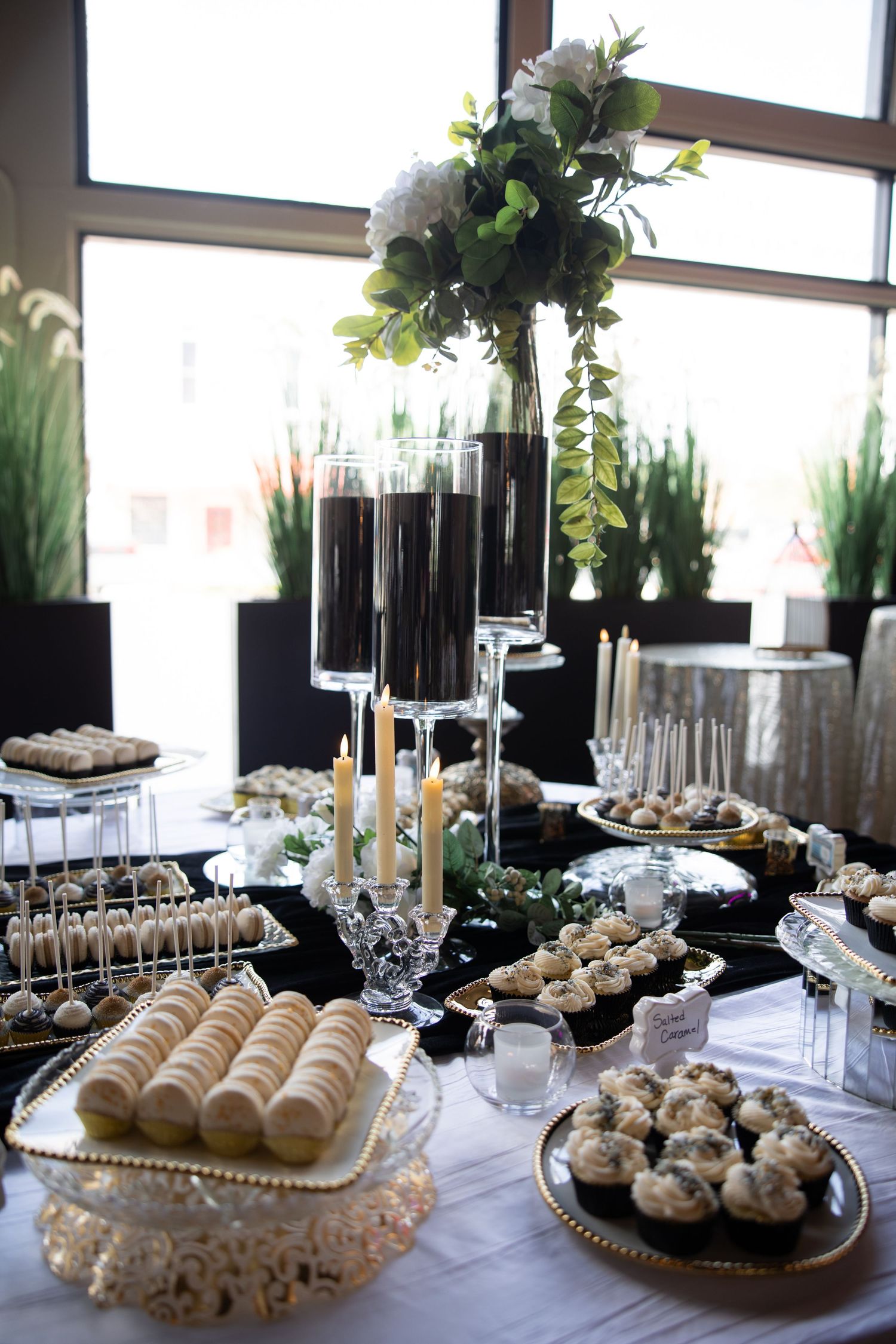 Elegant dessert display featuring white pastries and treats arranged on silver platters with floral decor.