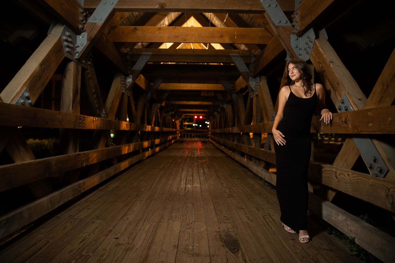 Sequential photos showing movement through a rustic wooden covered bridge at night.