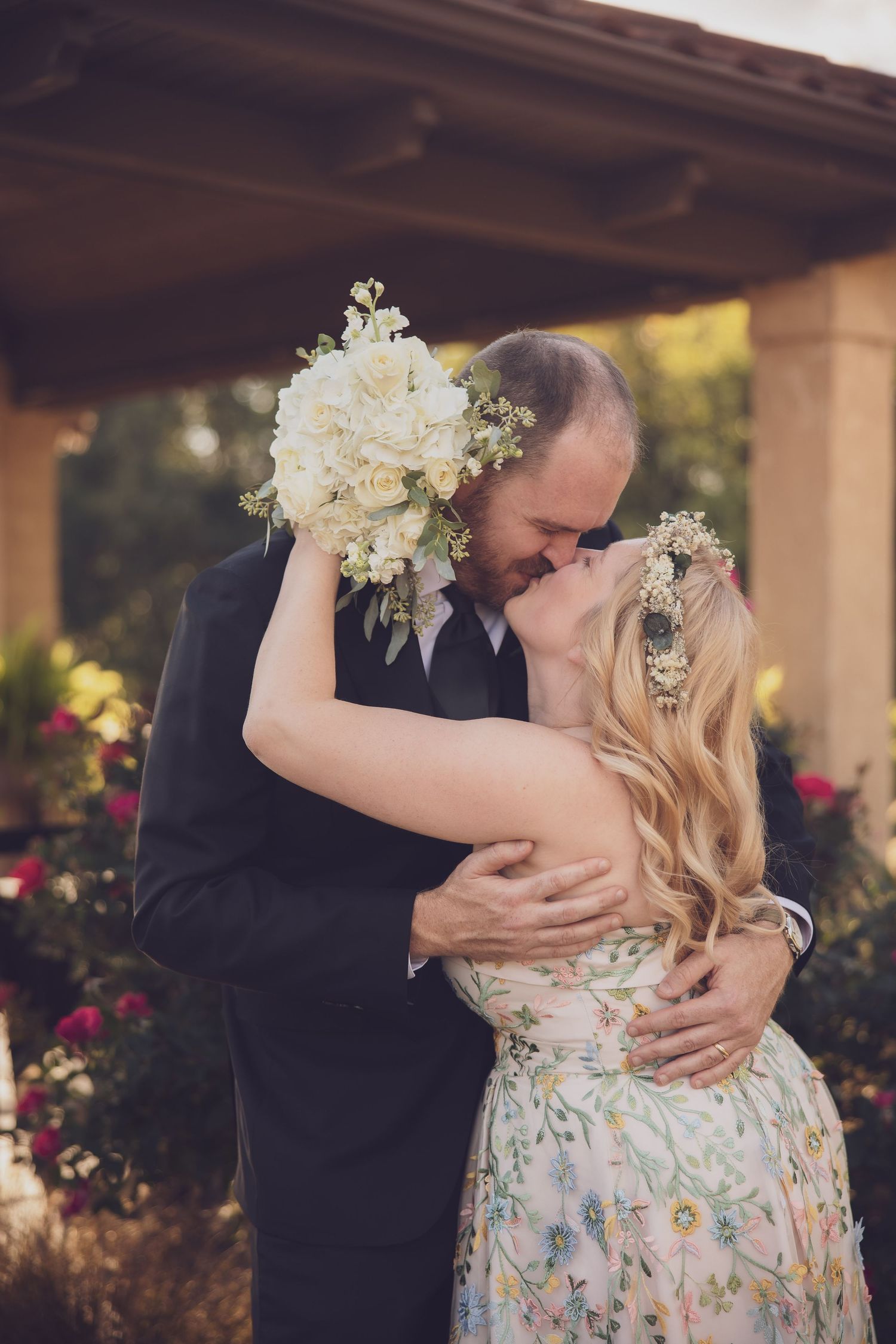 Romantic moment between newlyweds under a covered patio with floral decorations.