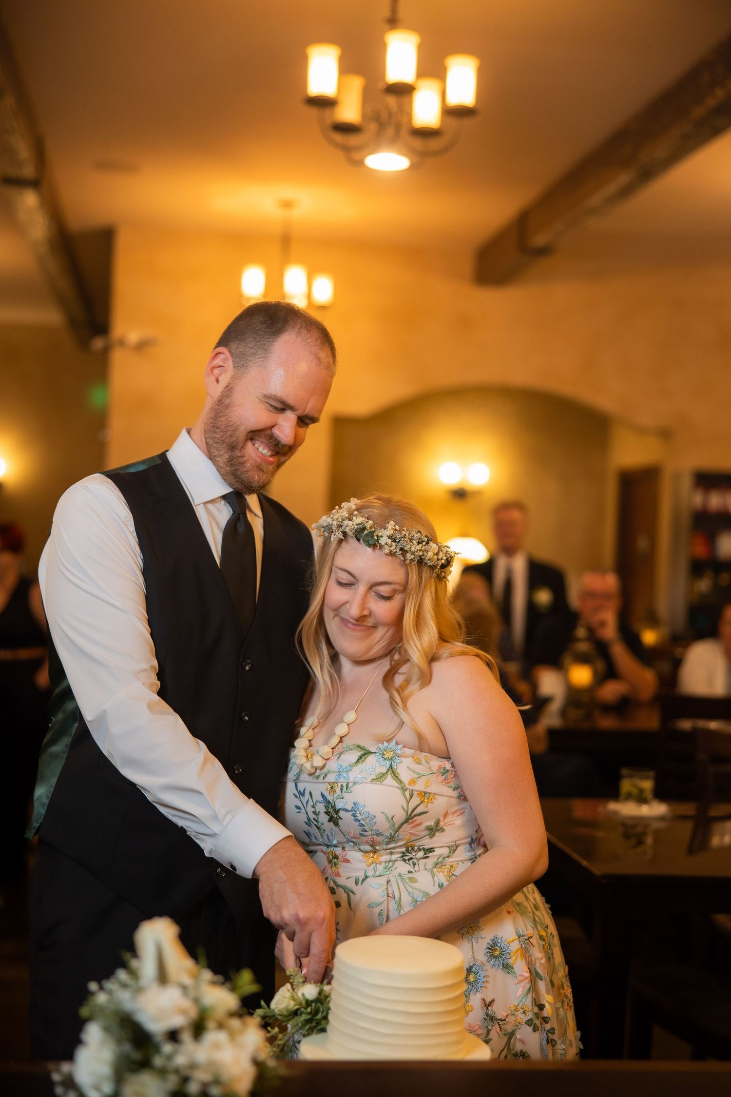 A couple cuts their simple white wedding cake together during their reception.