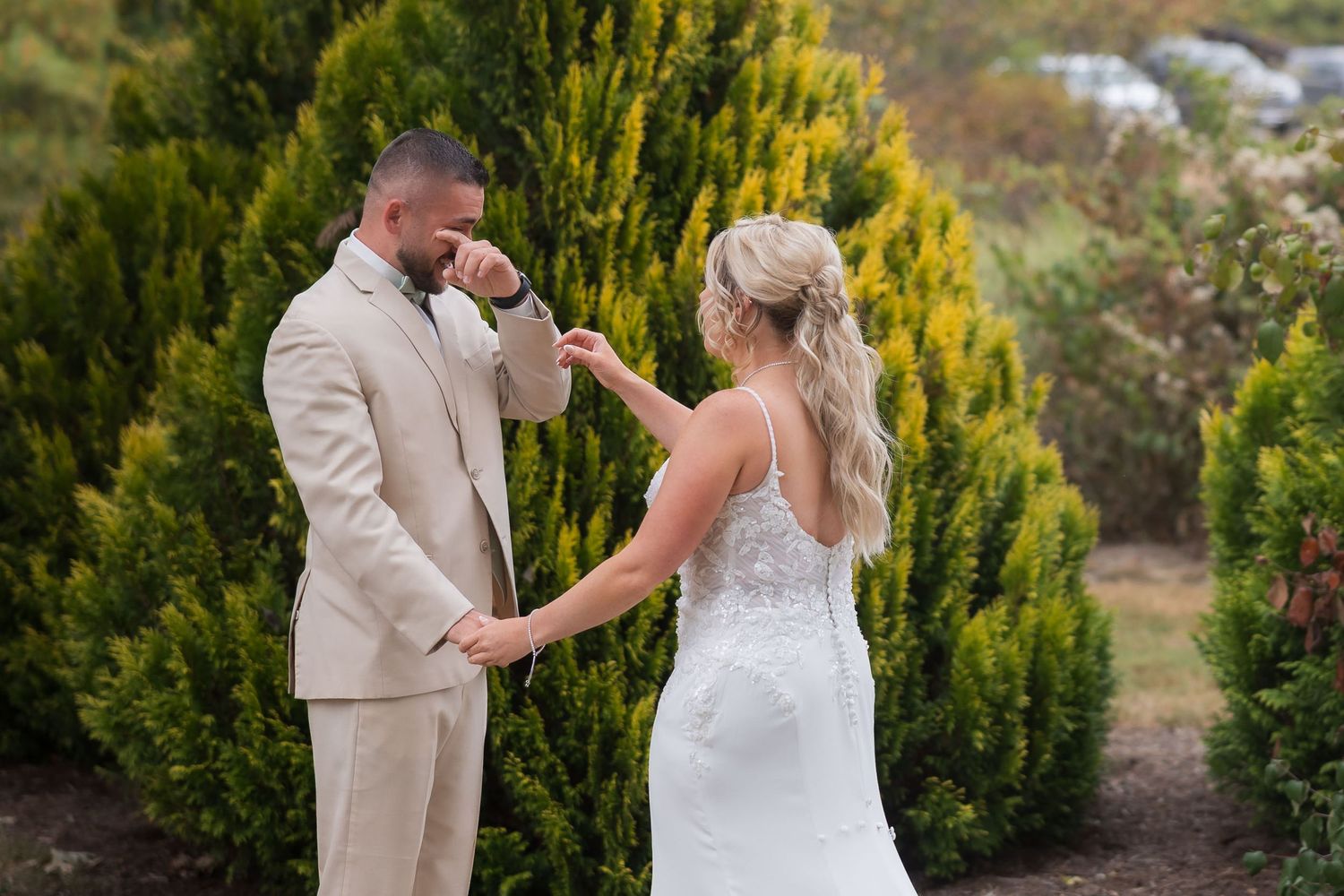 Candid wedding couple moments photographed by golden cypress trees in an outdoor garden setting.