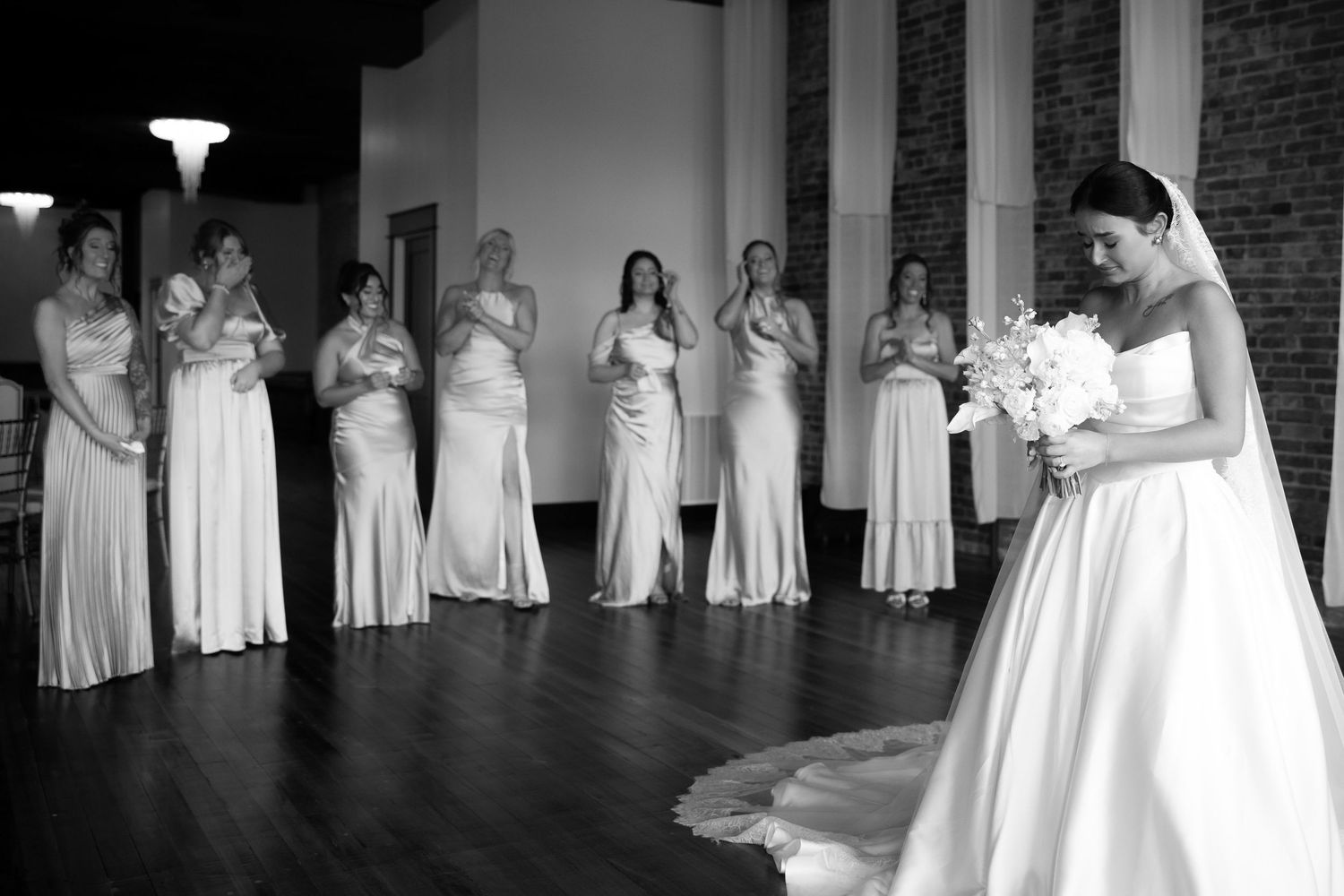 A row of bridesmaids in matching white dresses stand together during a wedding ceremony.