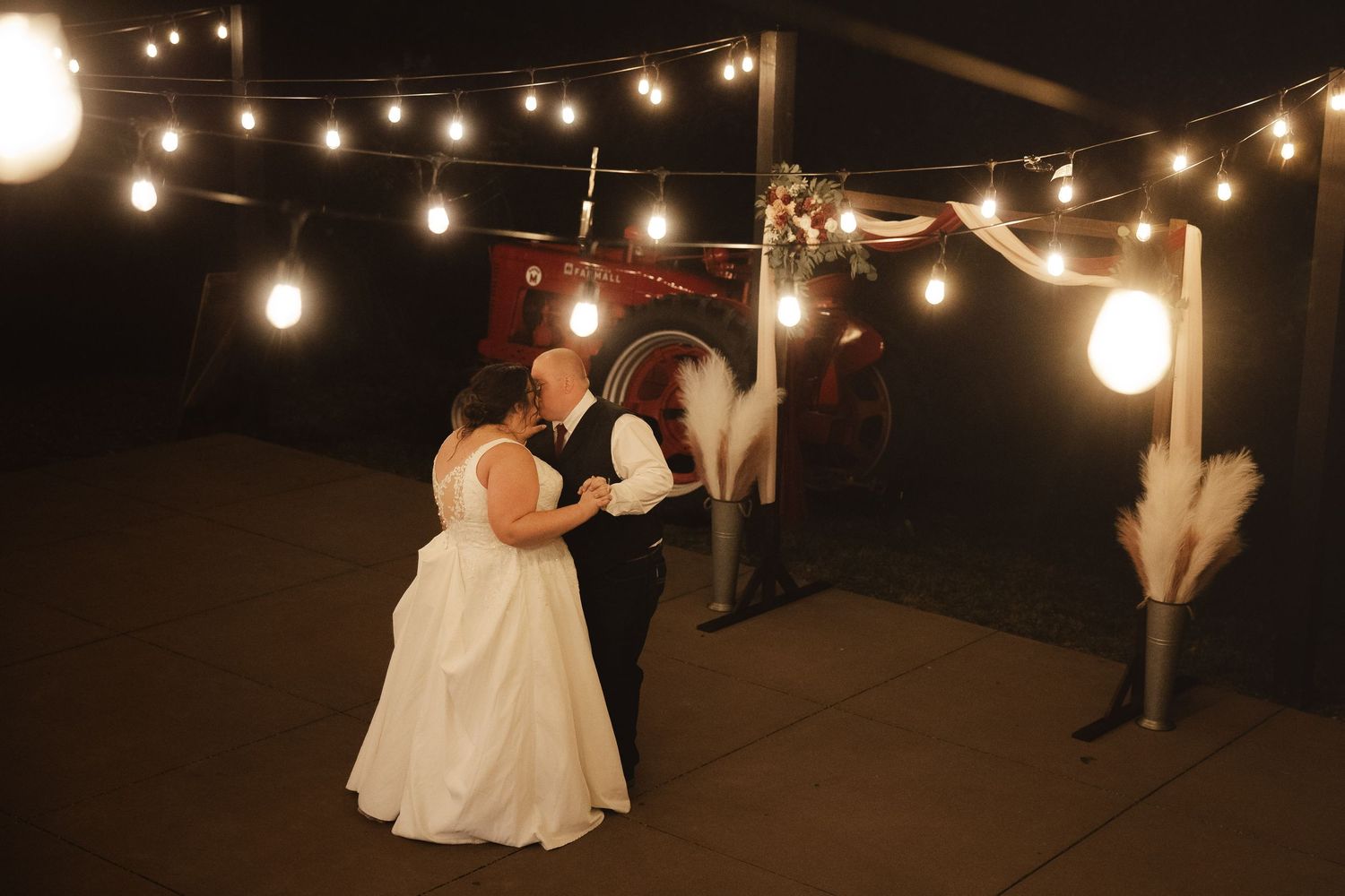 String lights create a romantic atmosphere at an outdoor evening wedding reception.