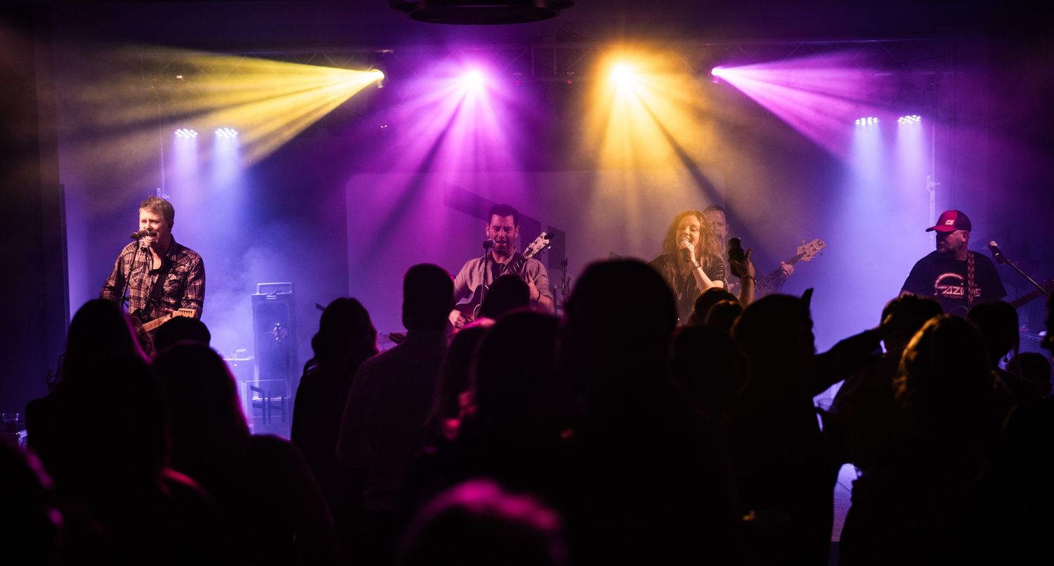 Concert-style lighting setup with purple and gold beams creating atmospheric effects.