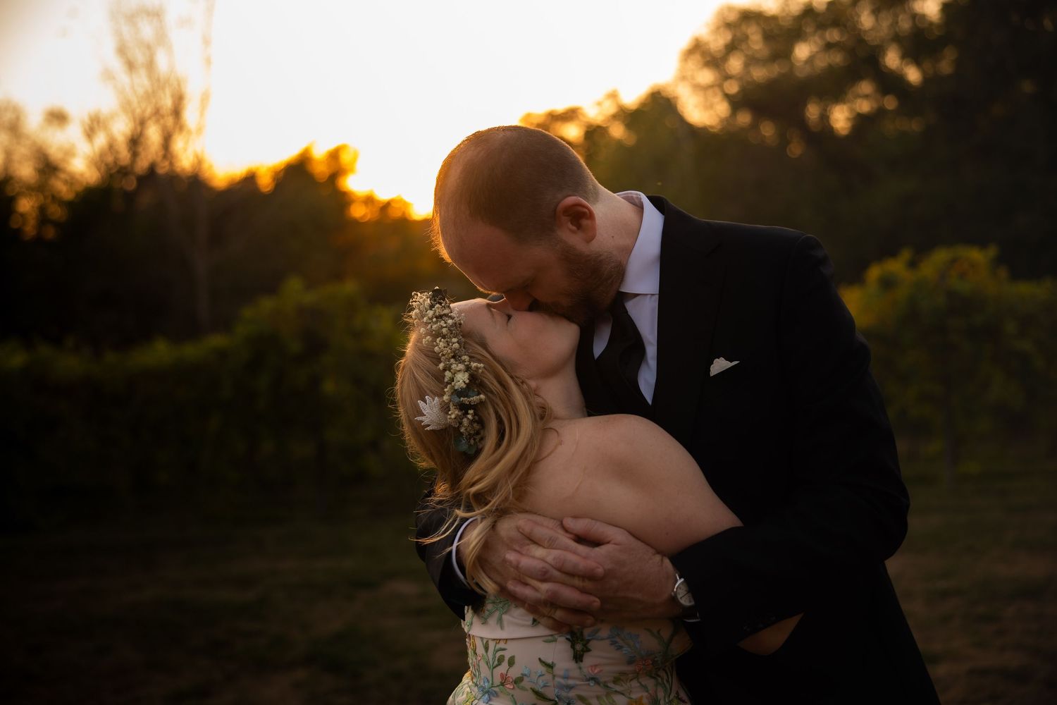 Romantic sunset moment between newlyweds in a vineyard setting.