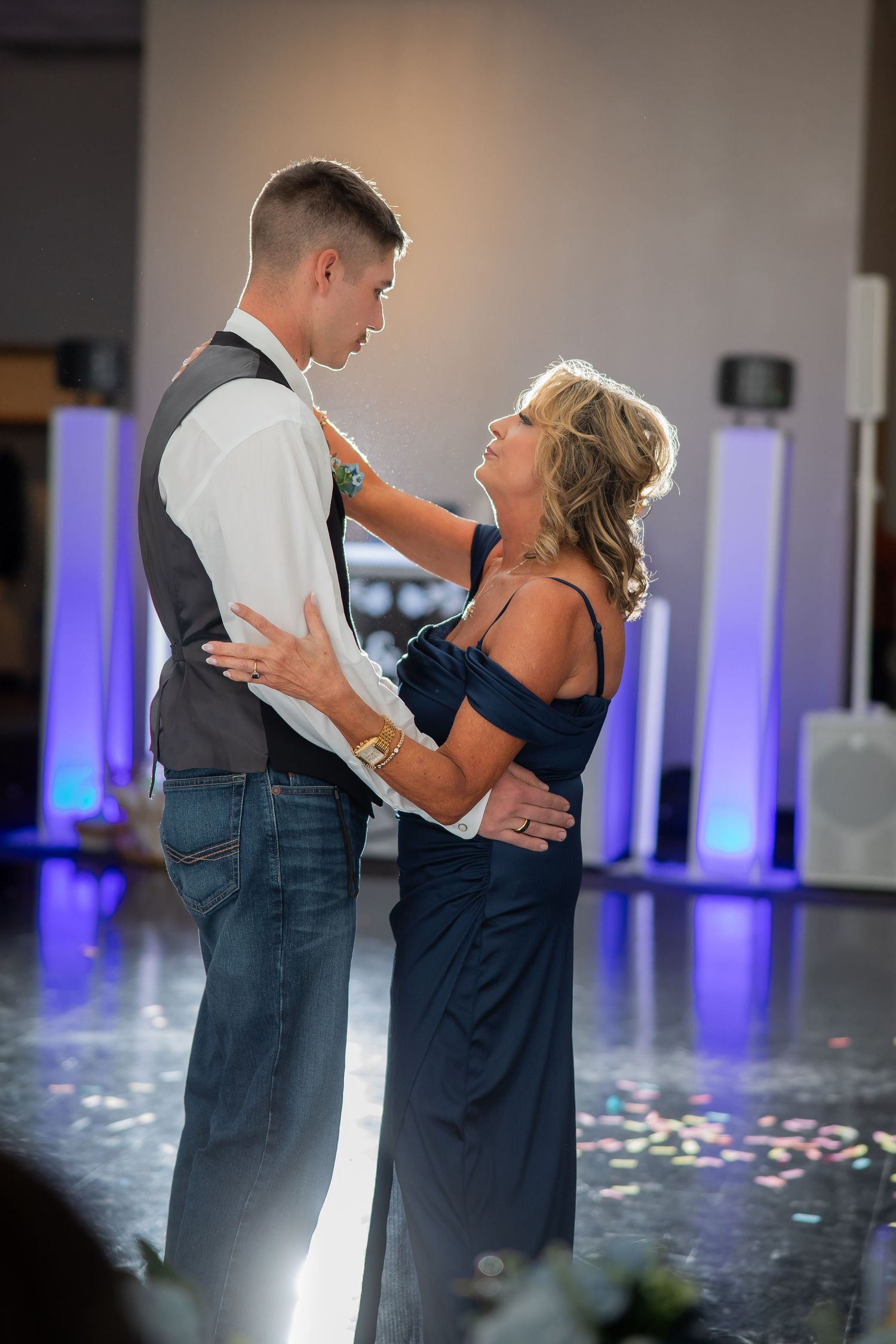 Groom shares tender mother-son dance with woman in navy gown at wedding reception.